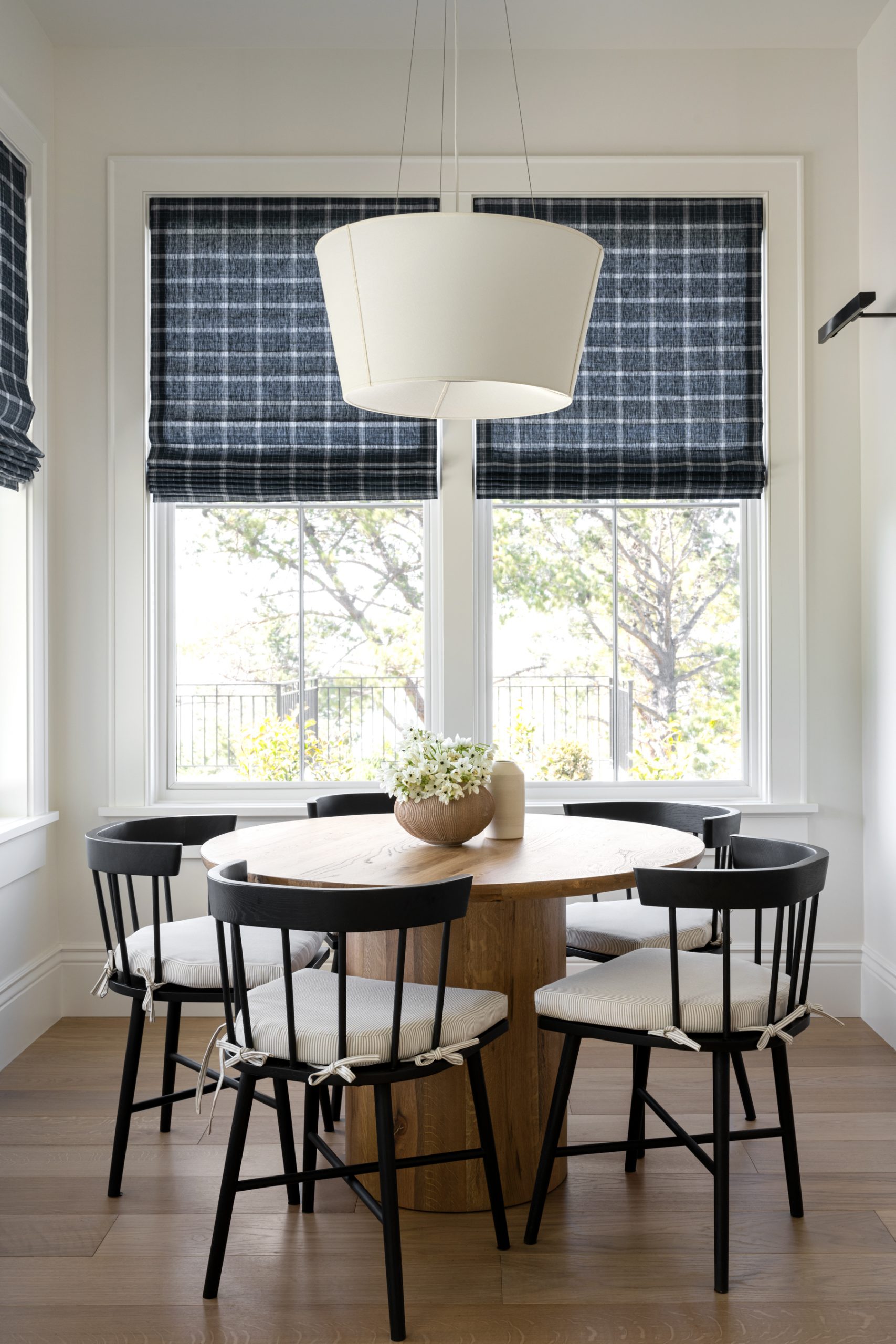 round dining table with black dining chairs with plaid shades