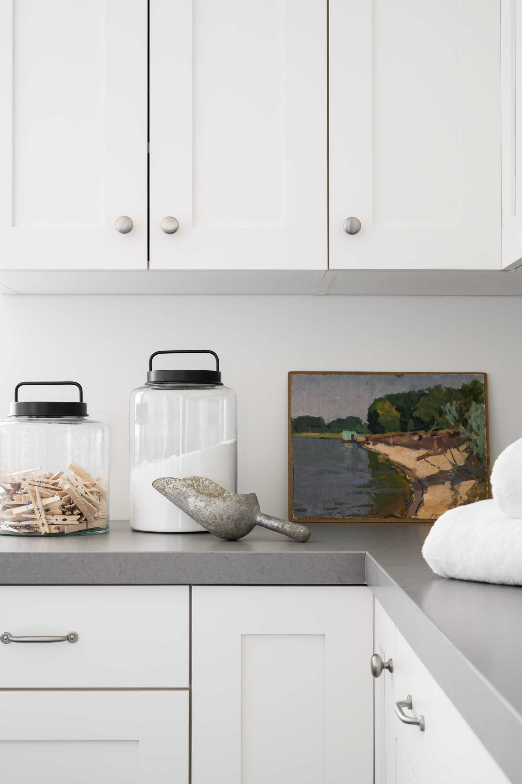 laundry room with white cabinetry and grey countertops with canisters and artwork