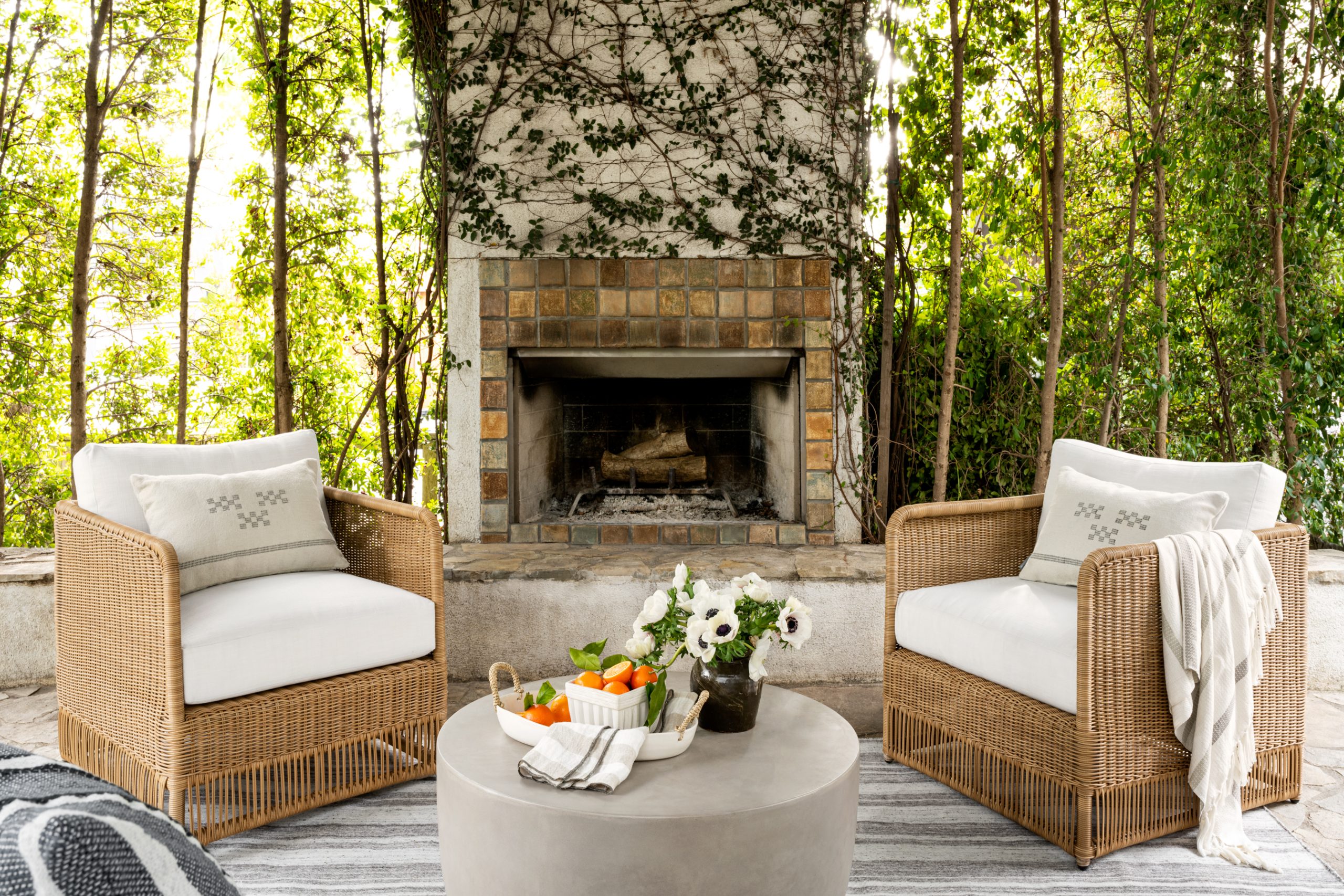 wicker lounge chairs with rug in front of outdoor fireplace