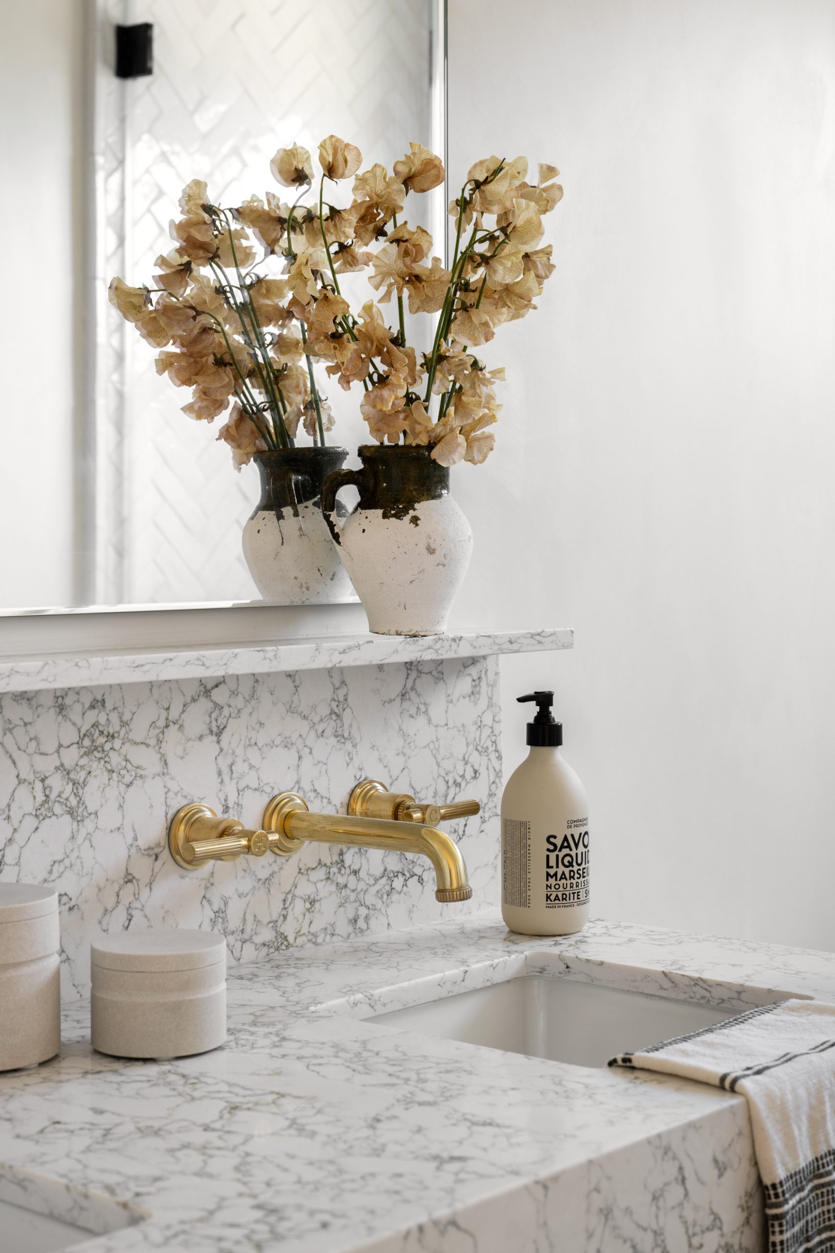 bathroom sink with white countertops and gold faucet