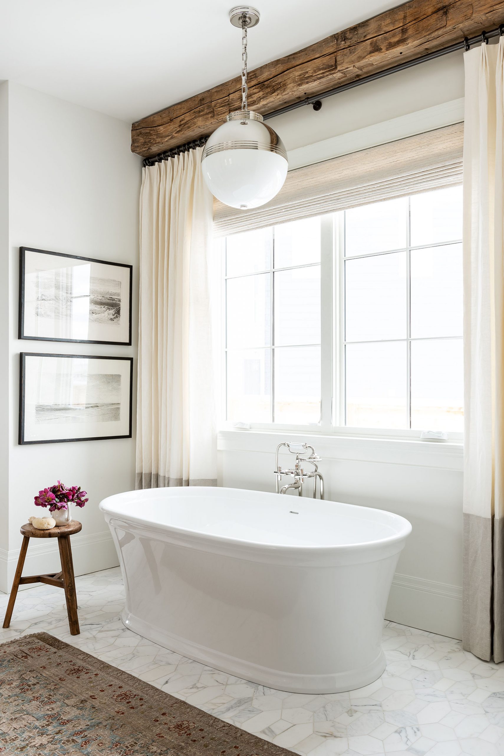 standing white bathtub with pendant hanging above