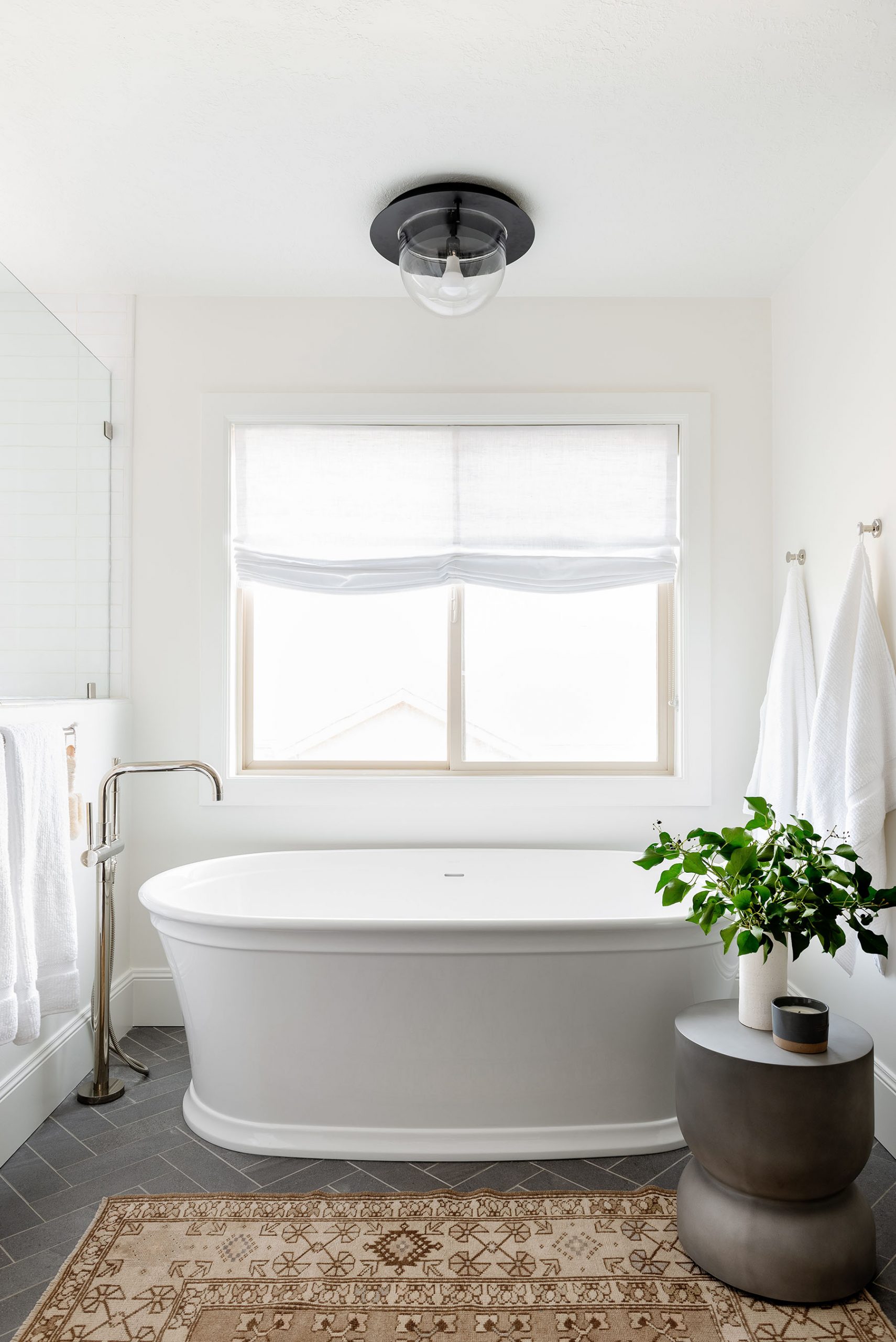 standing white bathtub with gray side table