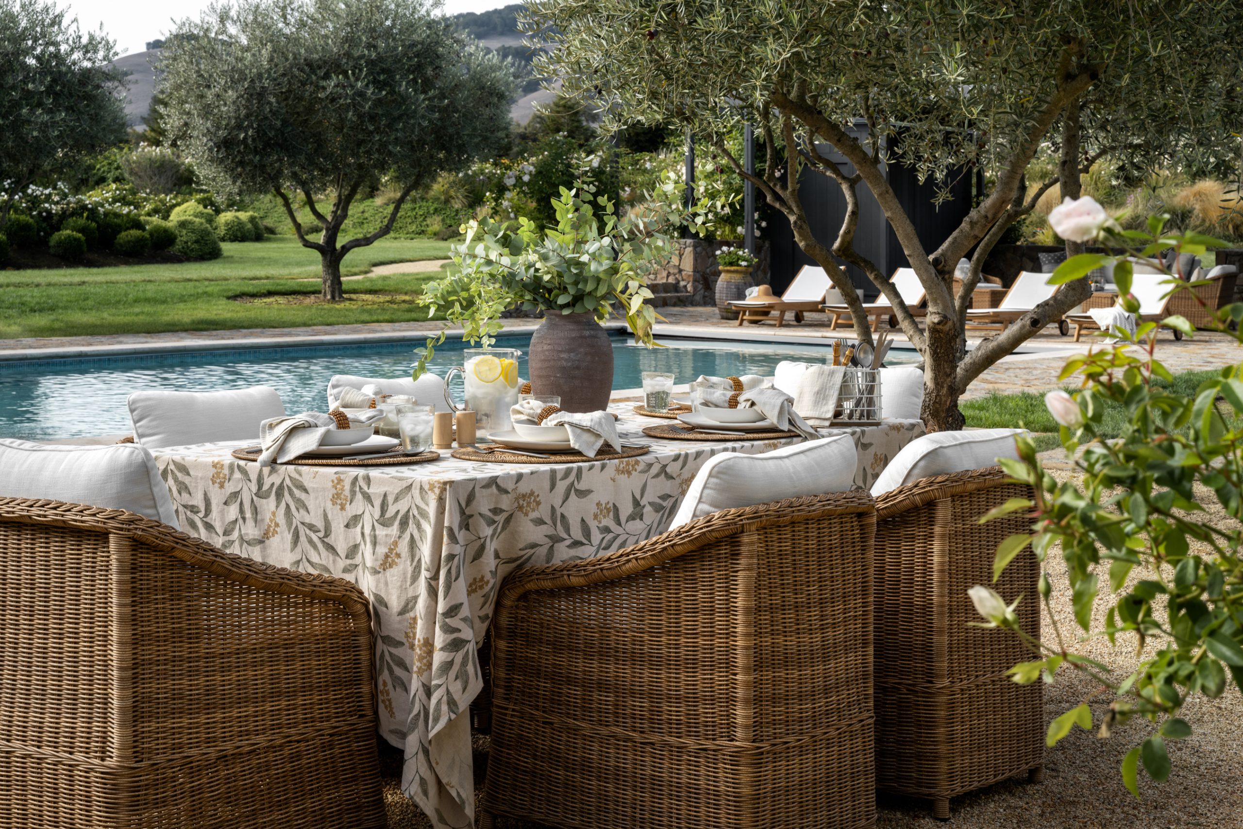 wicker outdoor dining chair around poolside tablescape