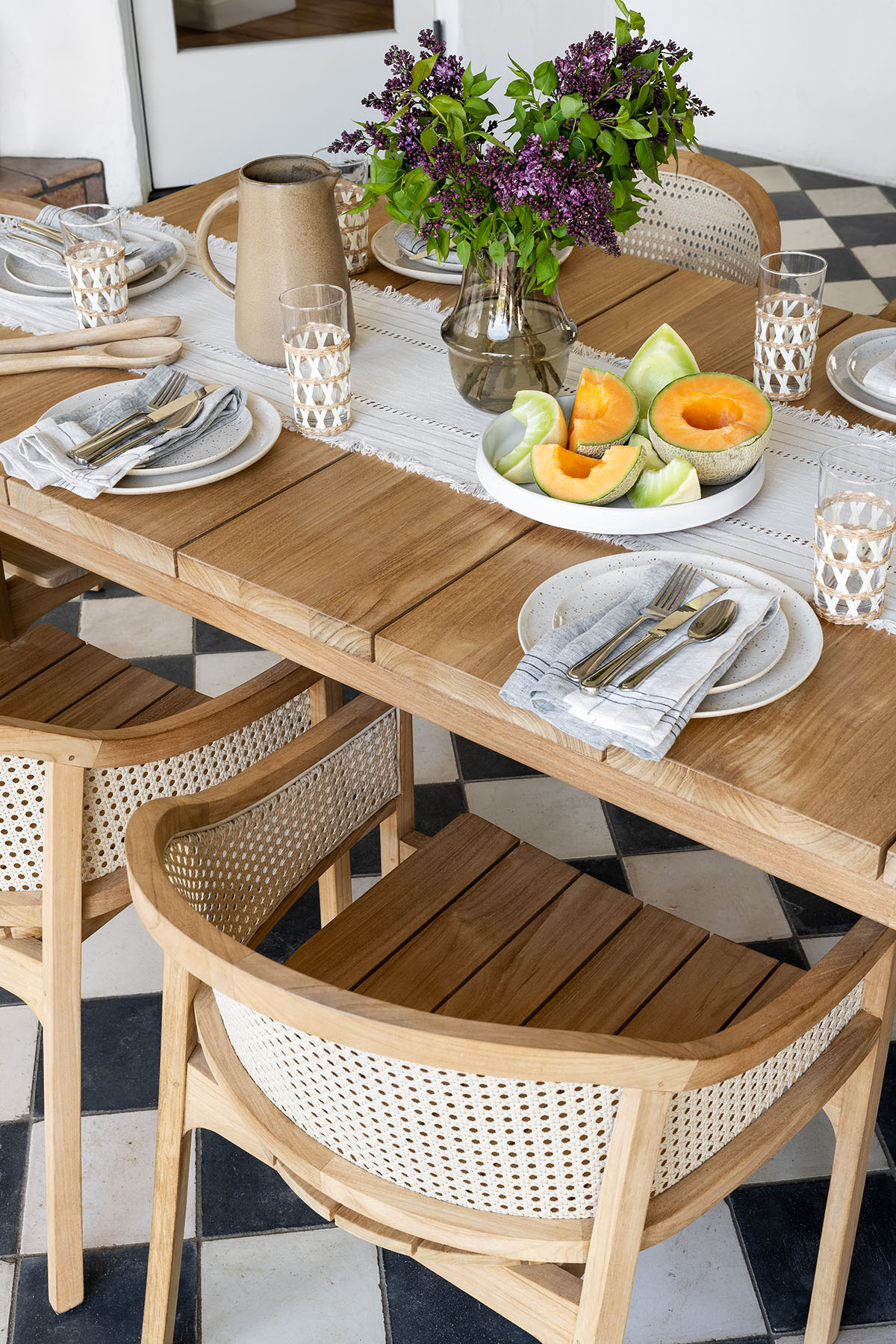outdoor teak wood dining chairs and table on checkerboard floor