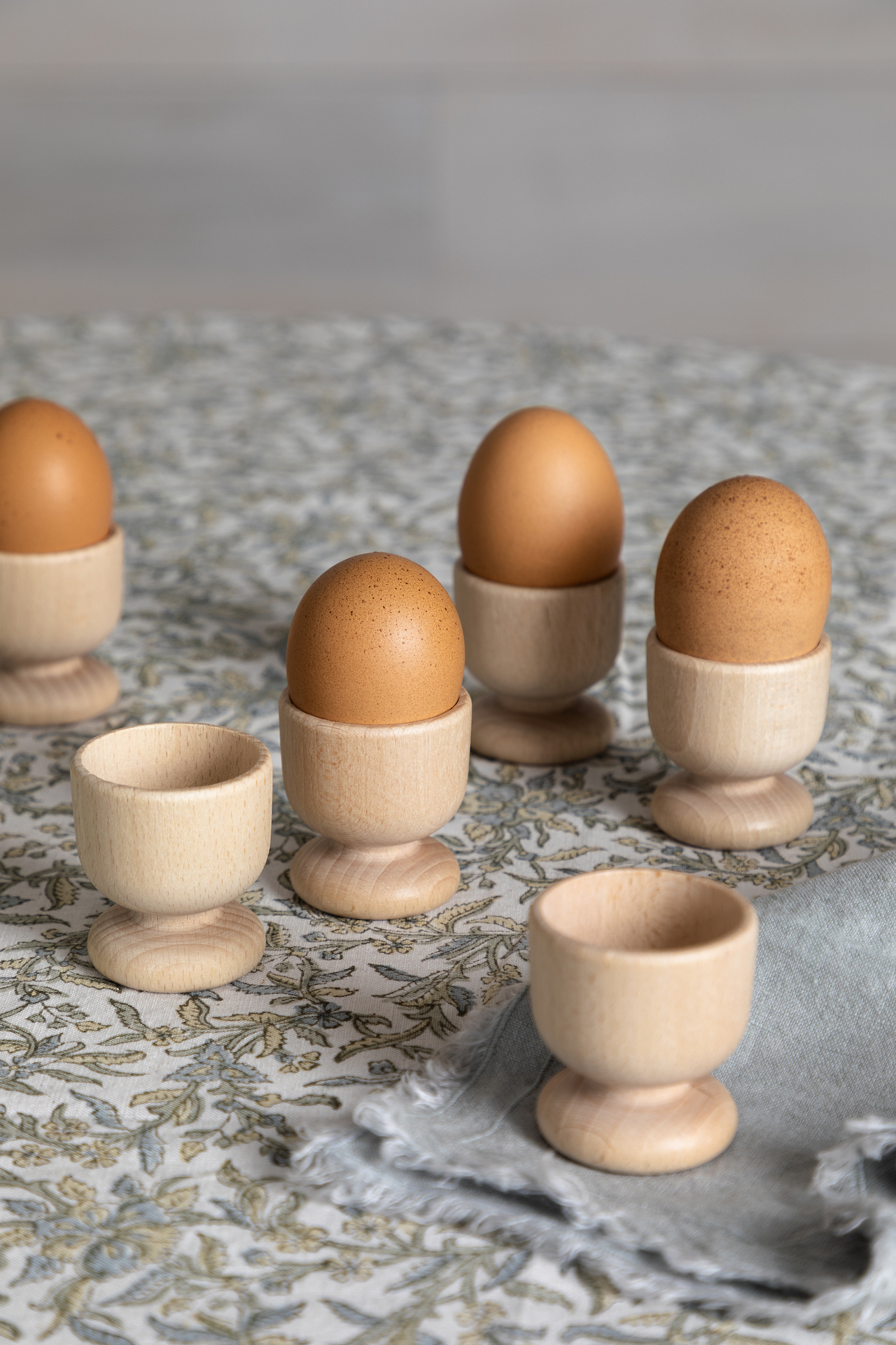 Eggs in wooden egg cup on blue floral tablecloth