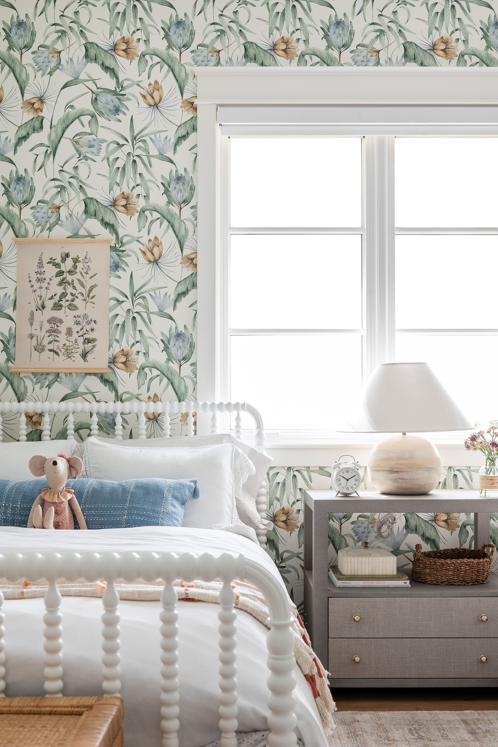 bedroom with green floral wallpaper and two white twin beds with one nightstand in the middle