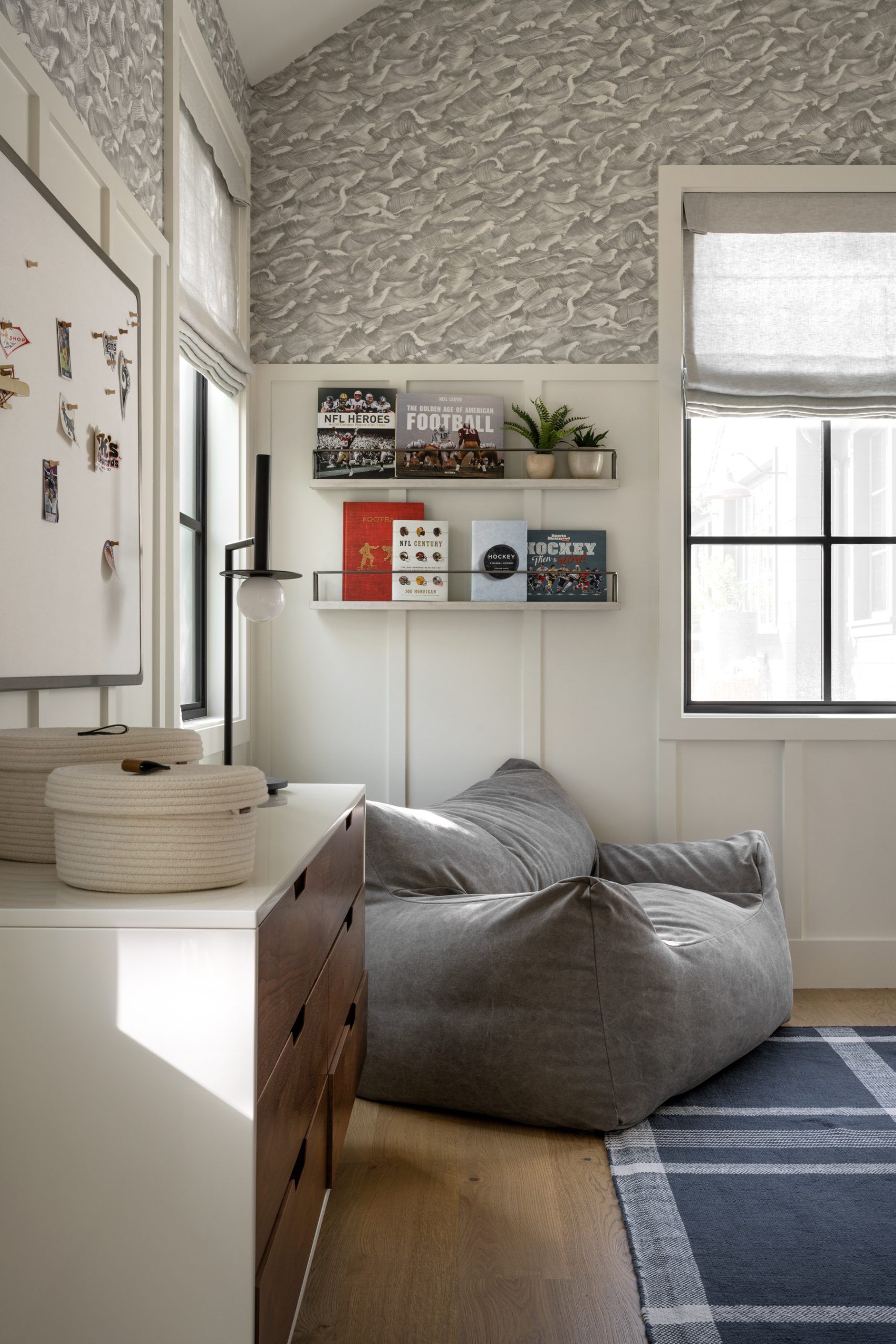 bedroom with gray chair and two shelves with books hanging above