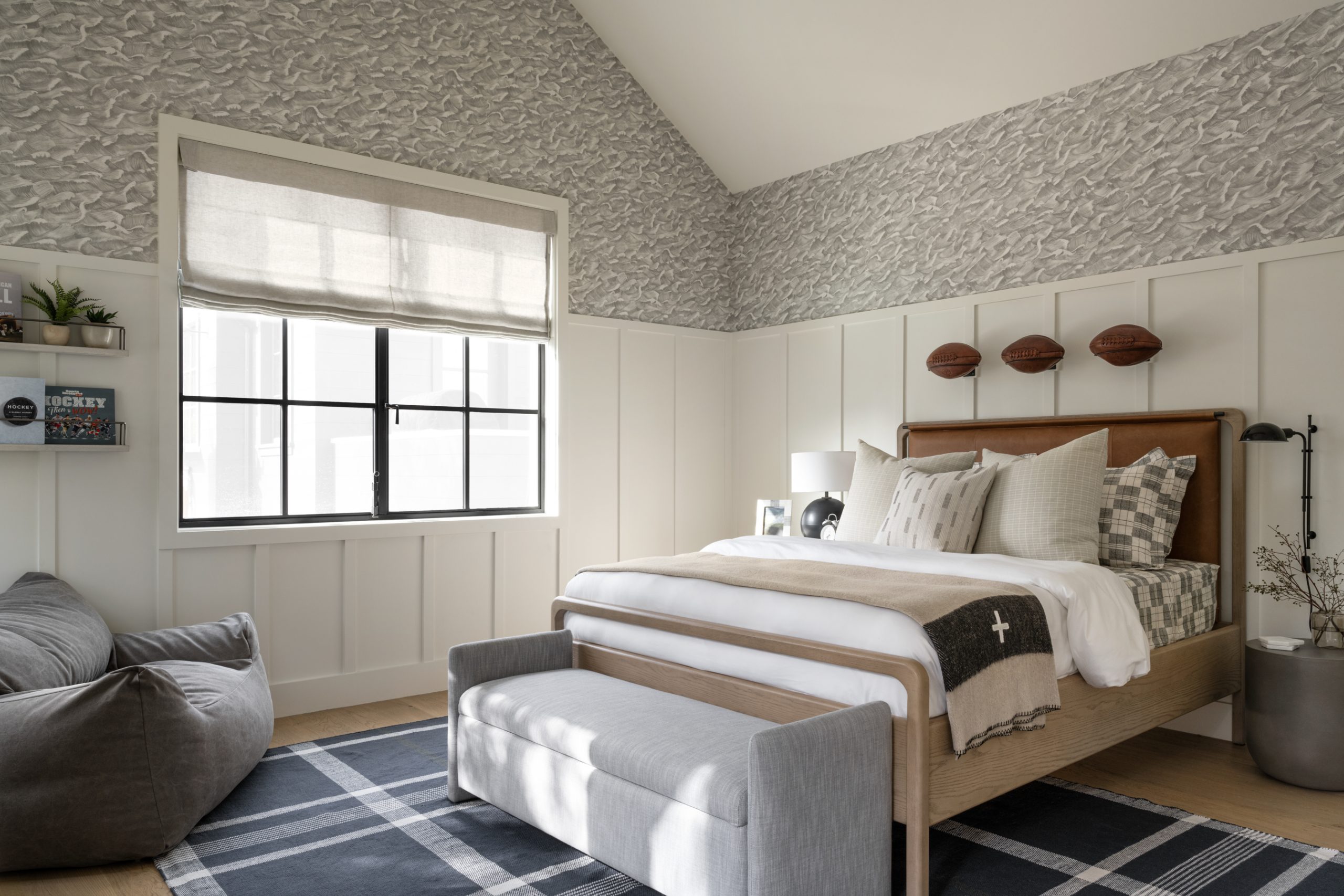 bedroom with wallpaper and paneled wood with leather bed and footballs hanging above