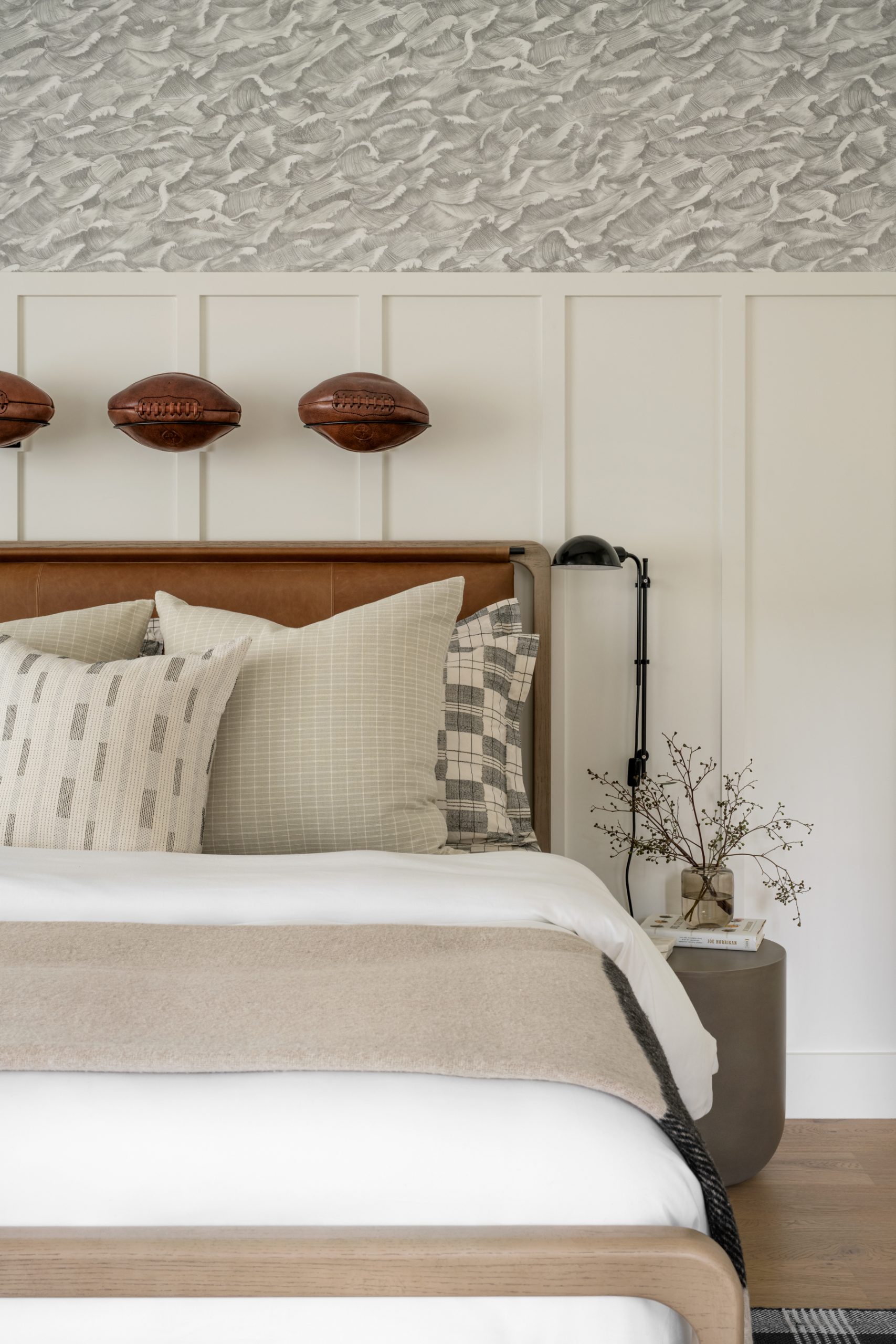 bedroom with wallpaper and paneled wood with leather bed and footballs hanging above