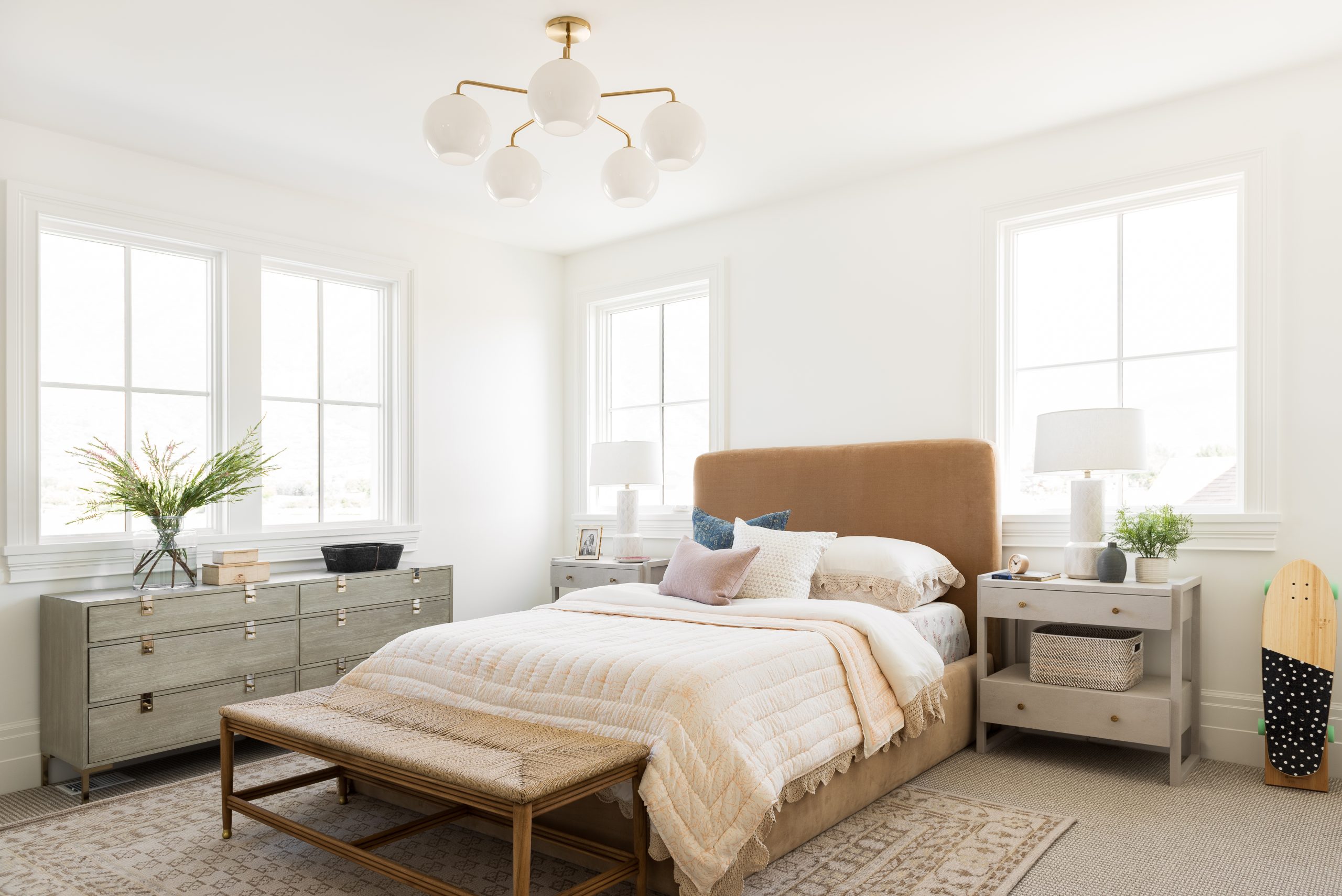 bedroom with tan velvet headboard and white nightstands