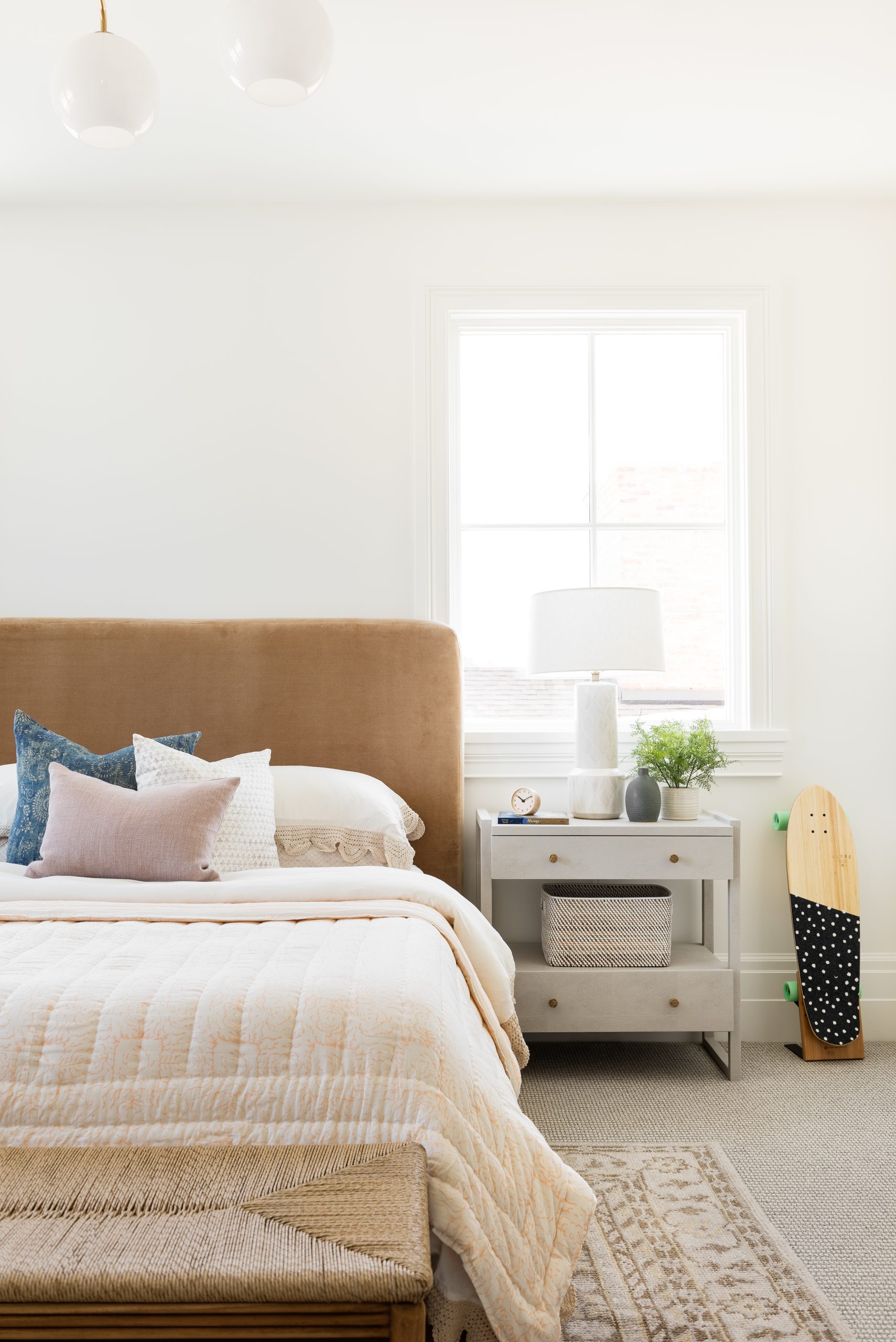 bedroom with tan velvet headboard and white nightstands