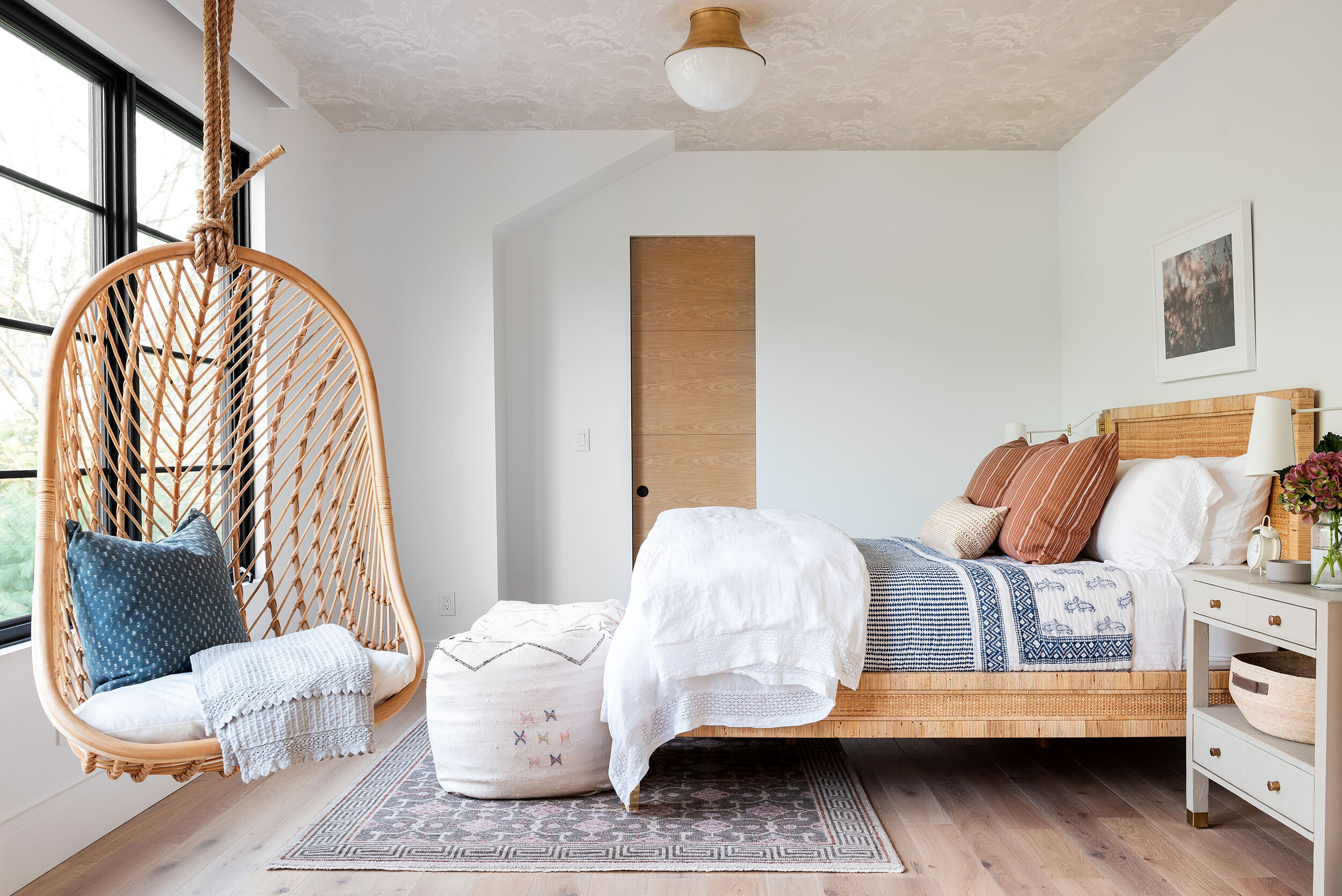 bedroom with natural wood bed frame and white nightstands with hanging chair