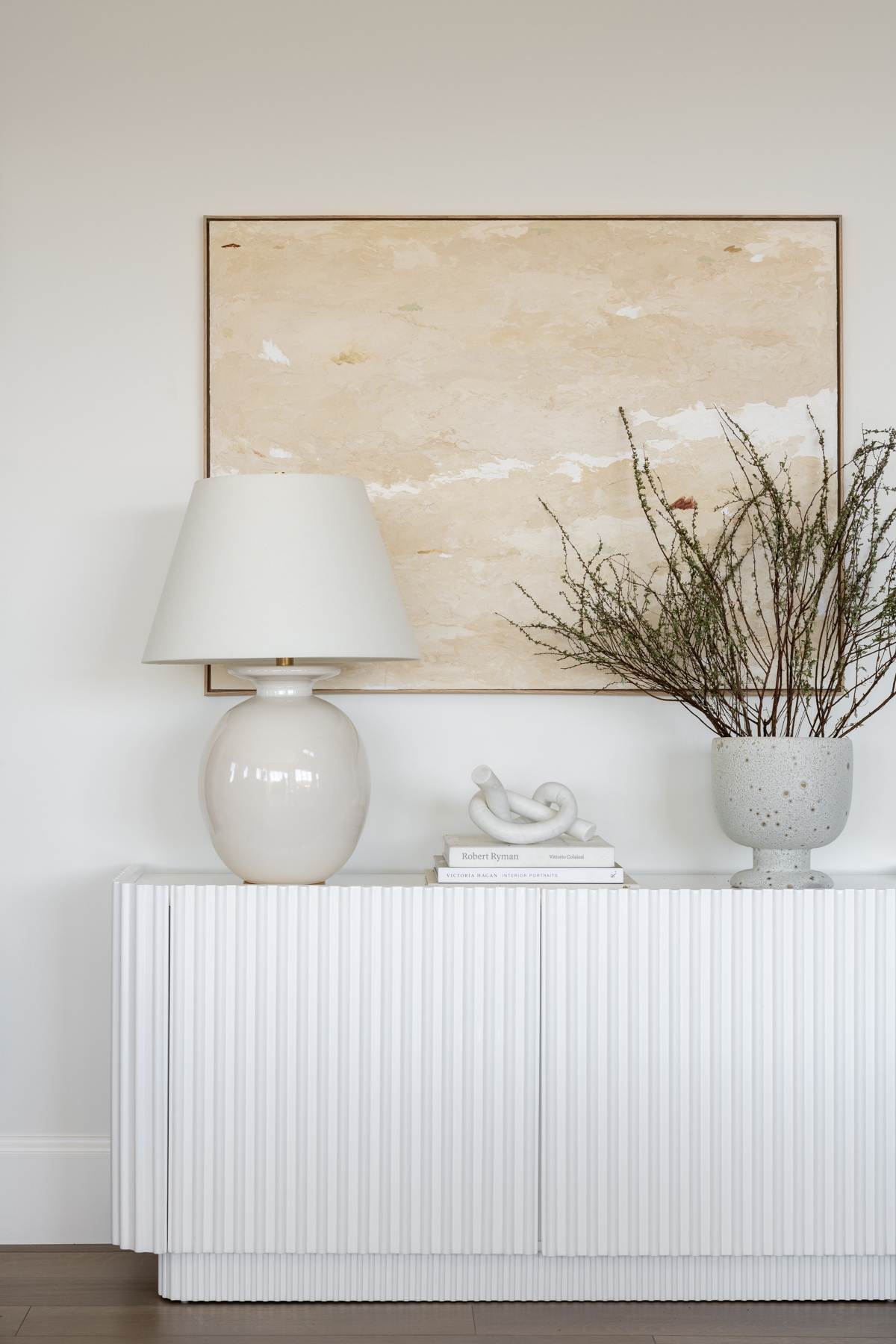 white console table with lamp, decor, and artwork