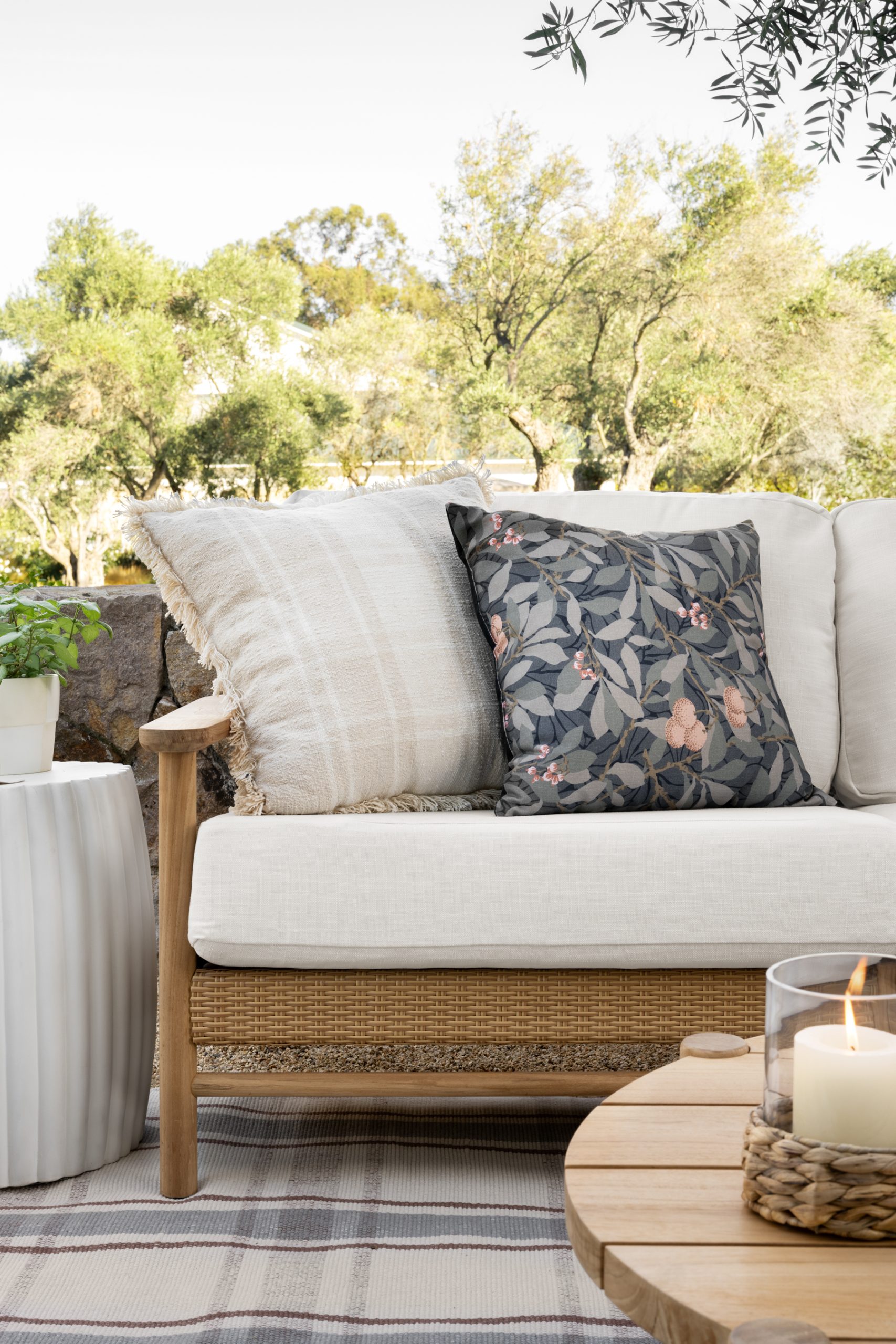 plaid and floral outdoor pillow on teak wood sofa