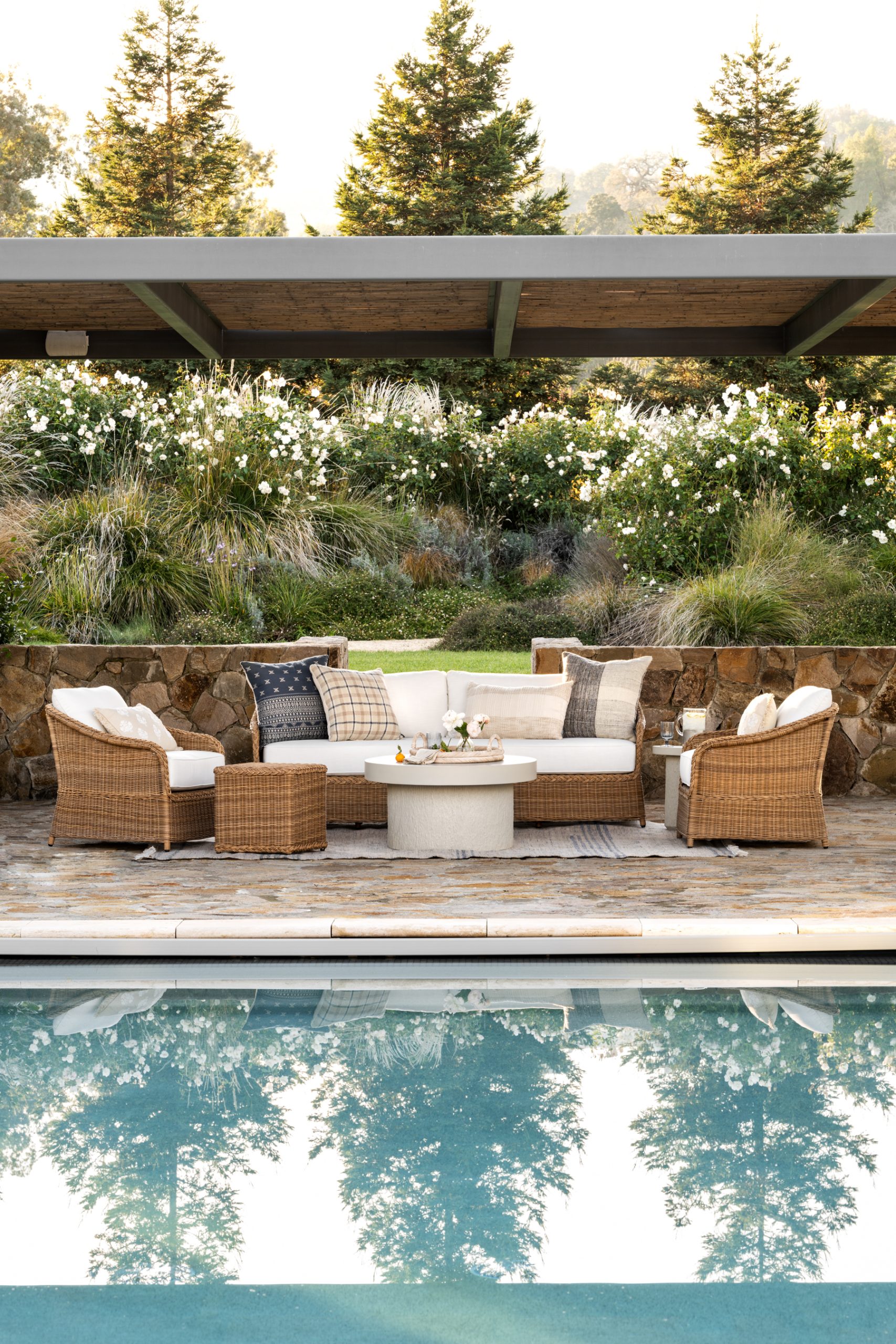 outdoor wicker lounge chairs and sofa around fiber stone coffee table by pool