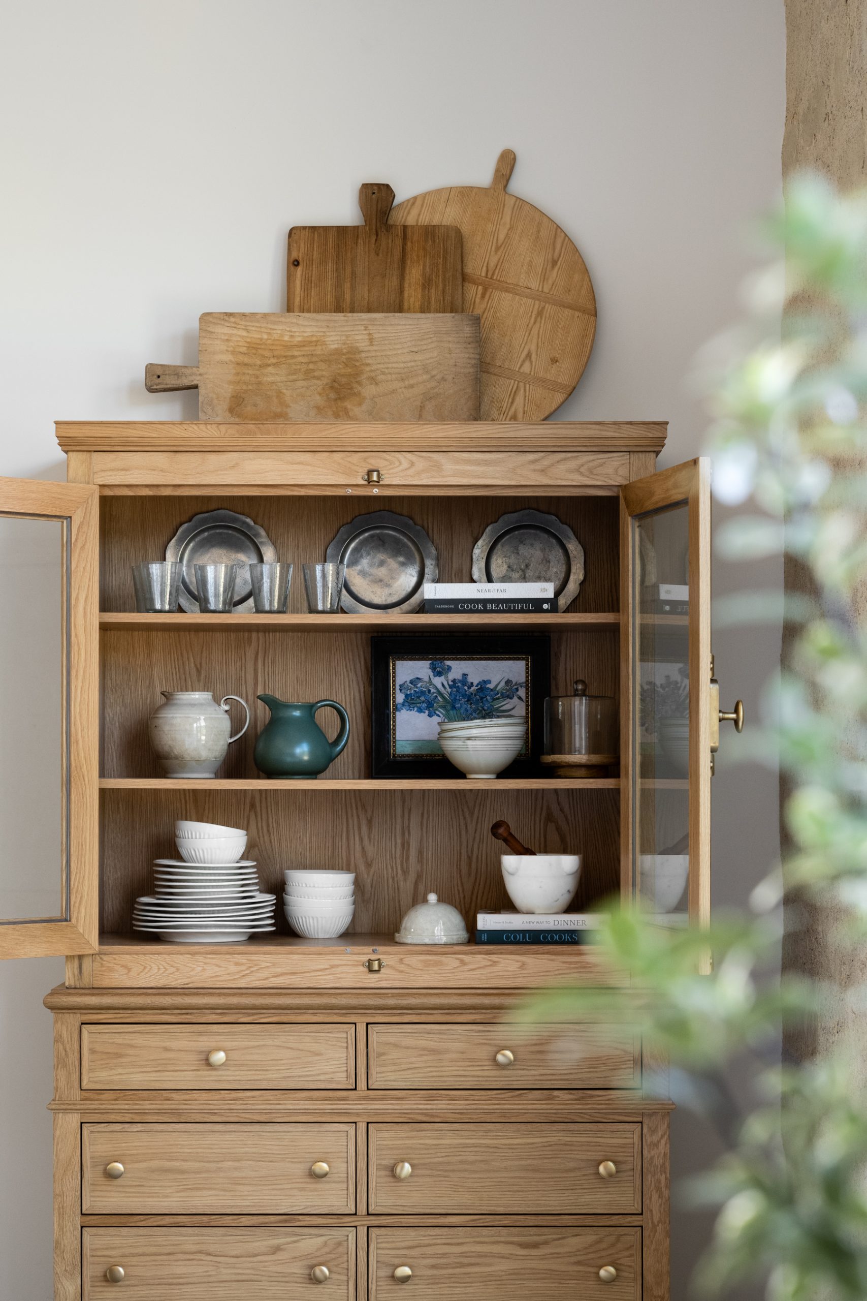wood cabinet with dinnerware and green vase