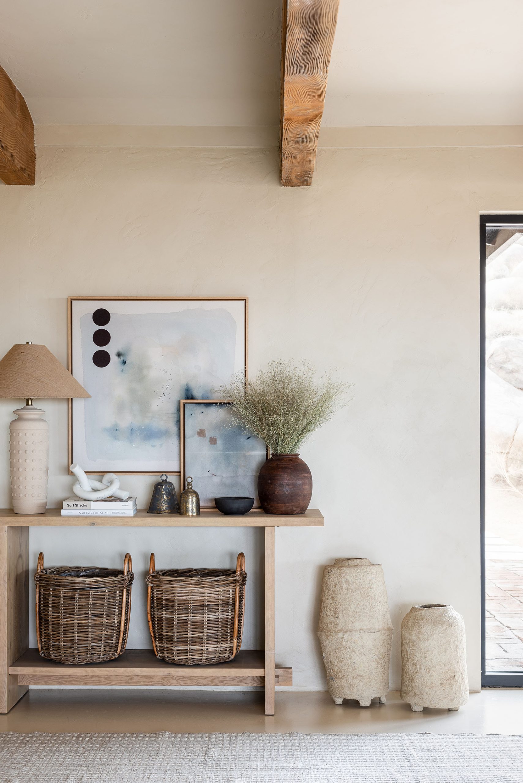 plaster vases next to console table styled with baskets and artwork