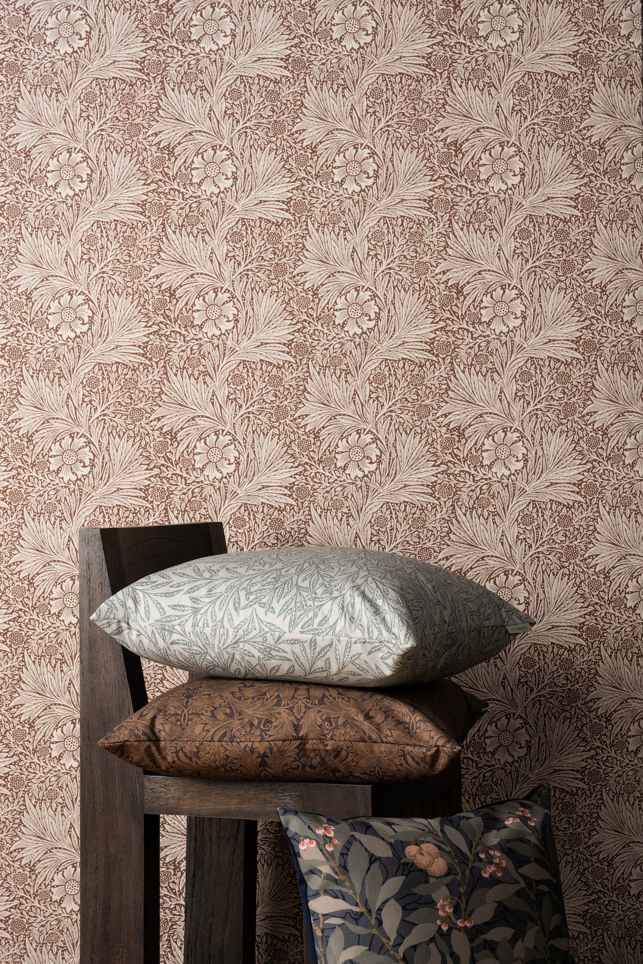 red tone floral wallpaper with chair and stacked pillows