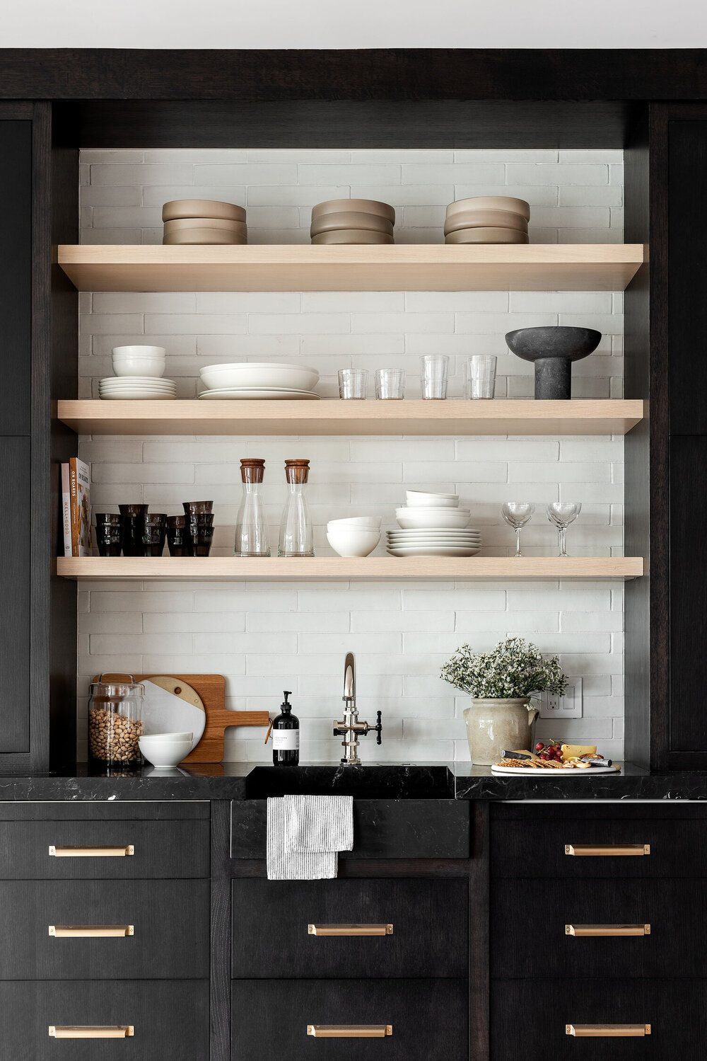 kitchenette with dark cabinets and white oak floating shelves