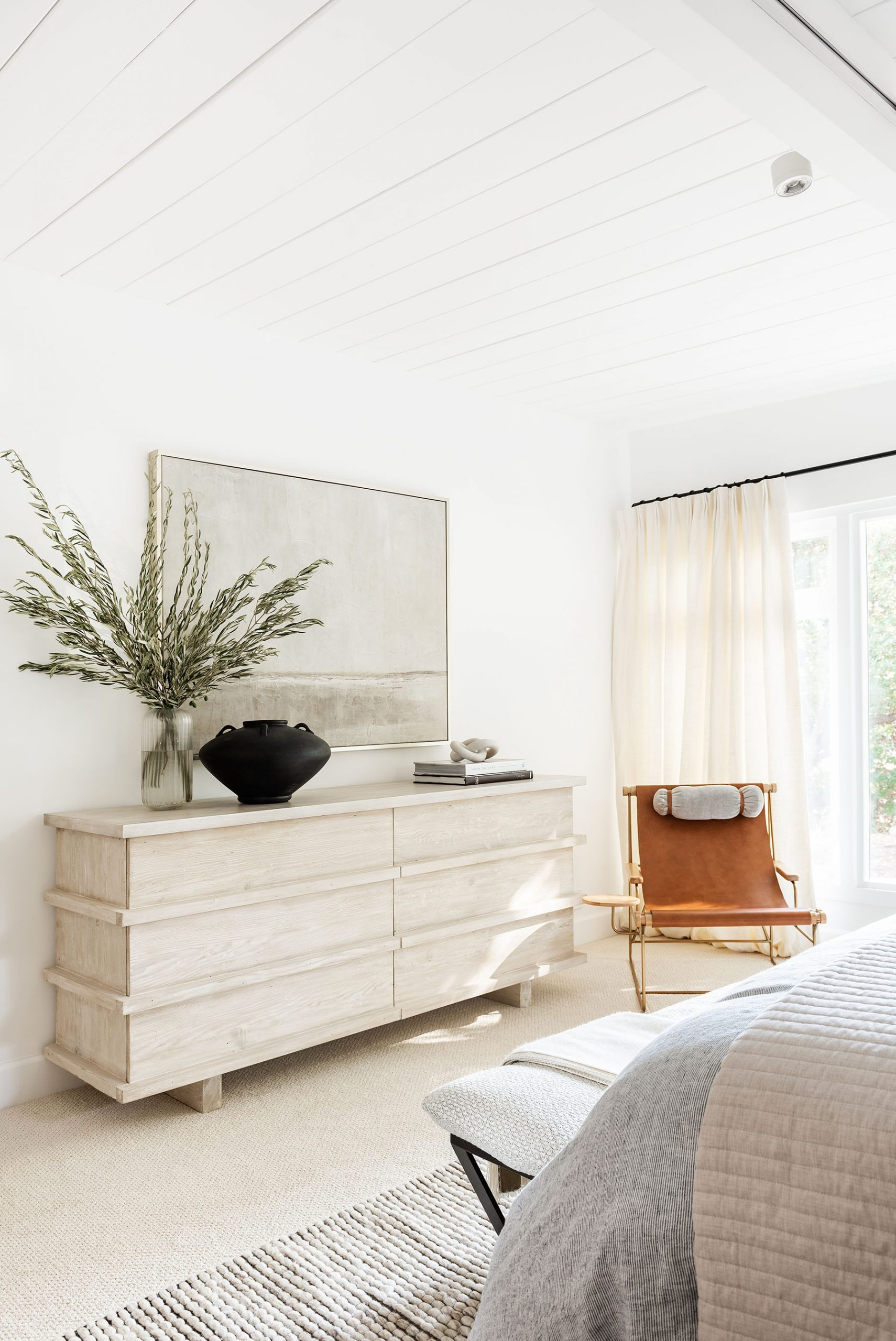Wood dresser in bedroom with coastal artwork
