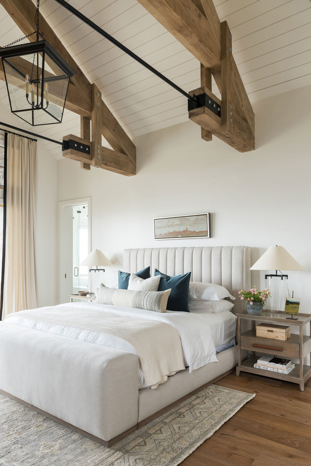 Bedroom with upholstered bed and wood beams on ceiling