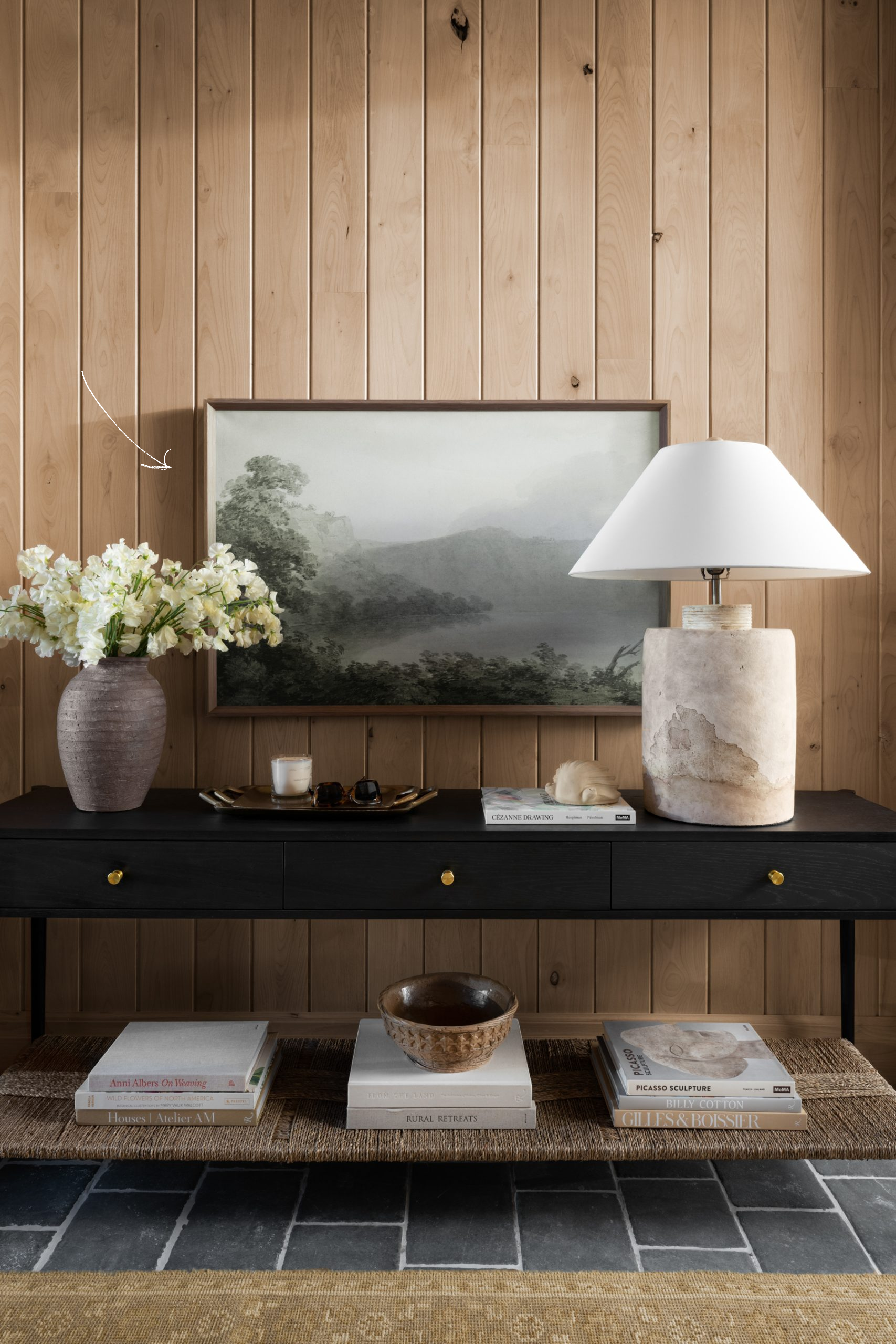 black console styled with decor in wood paneled entryway