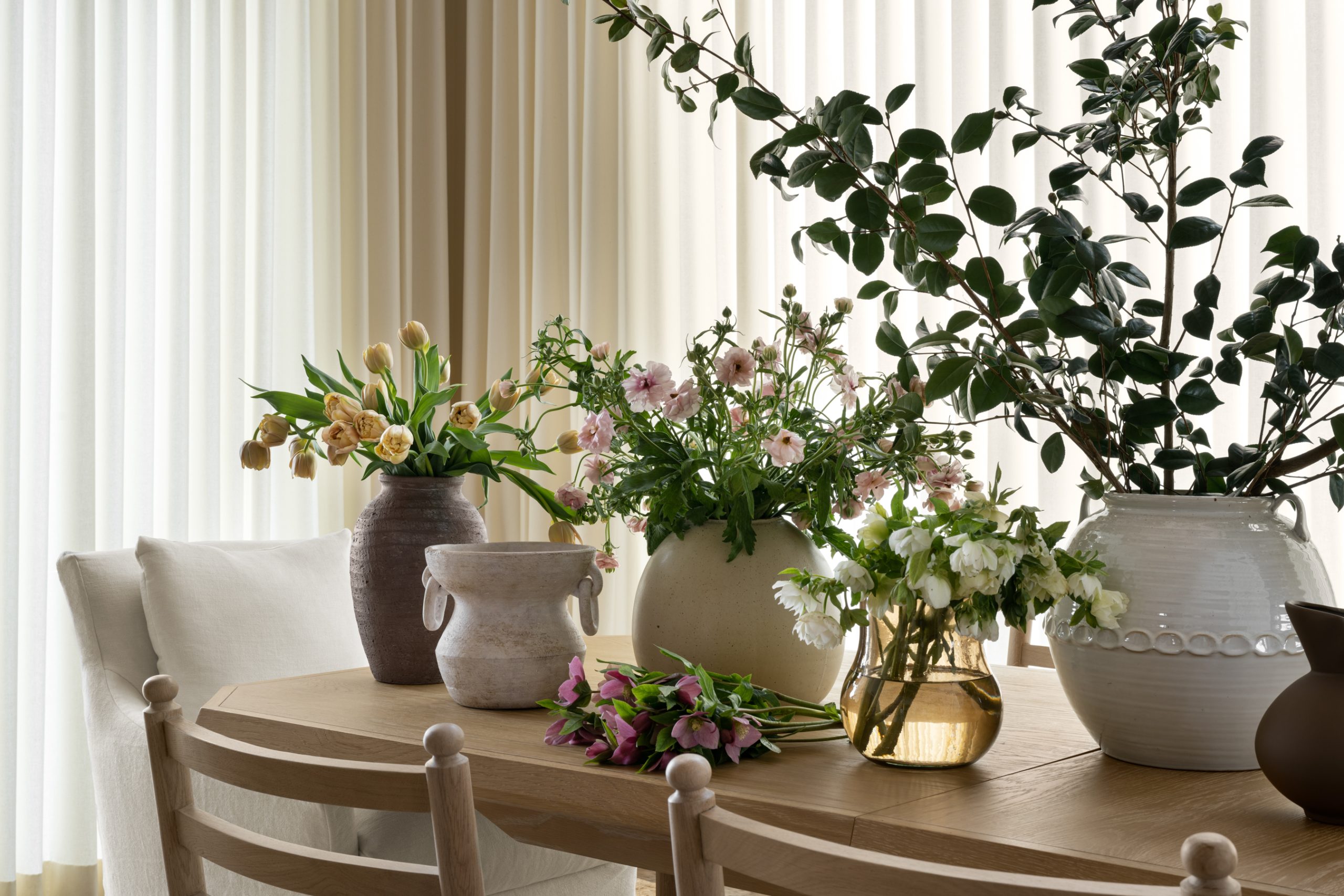 dining table with vases of flowers and greenery