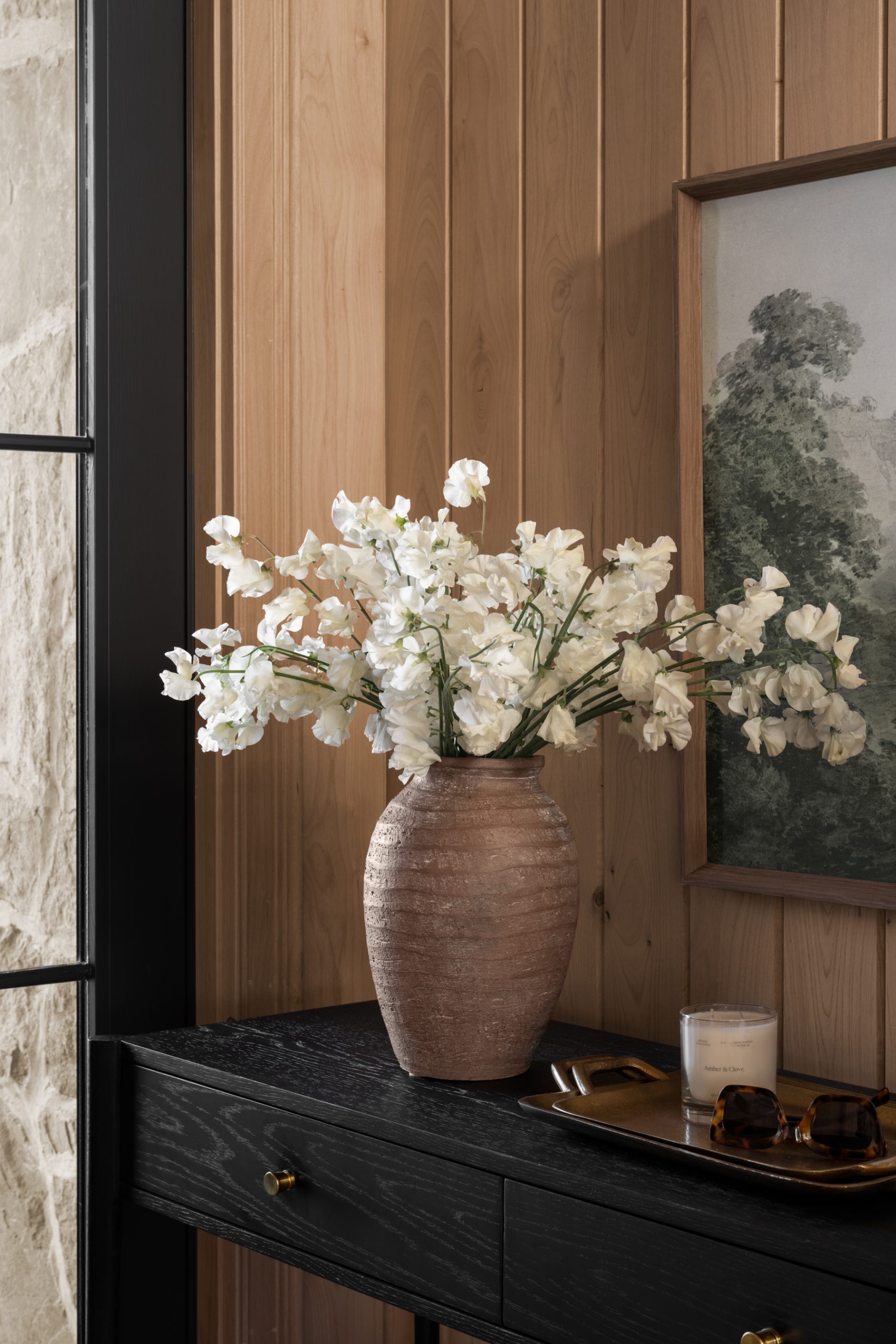 brown vase with white flowers on black console table in entry