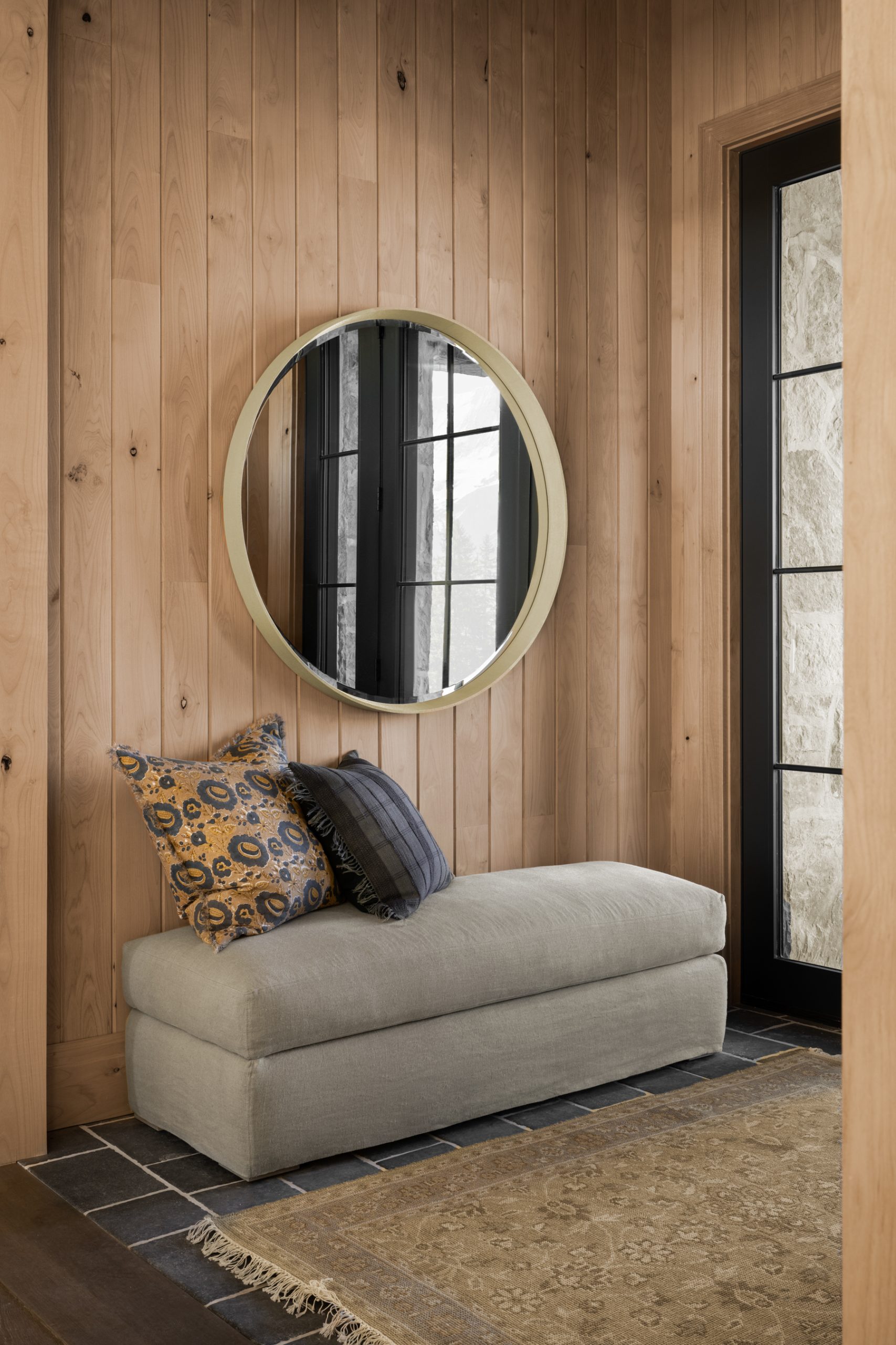 bench and mirror in wood paneled entryway