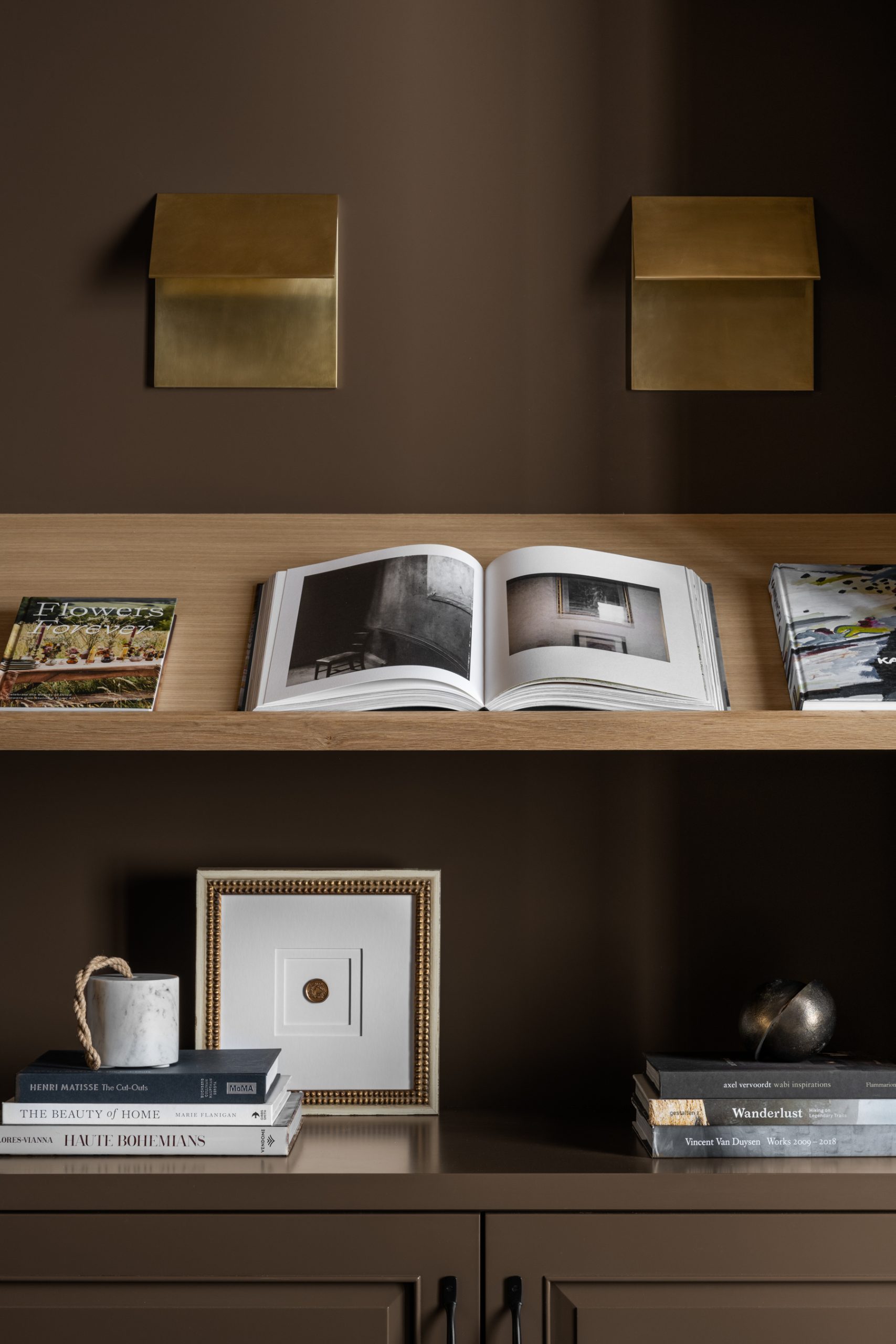 brown moody office open shelves with books, artwork, and decor