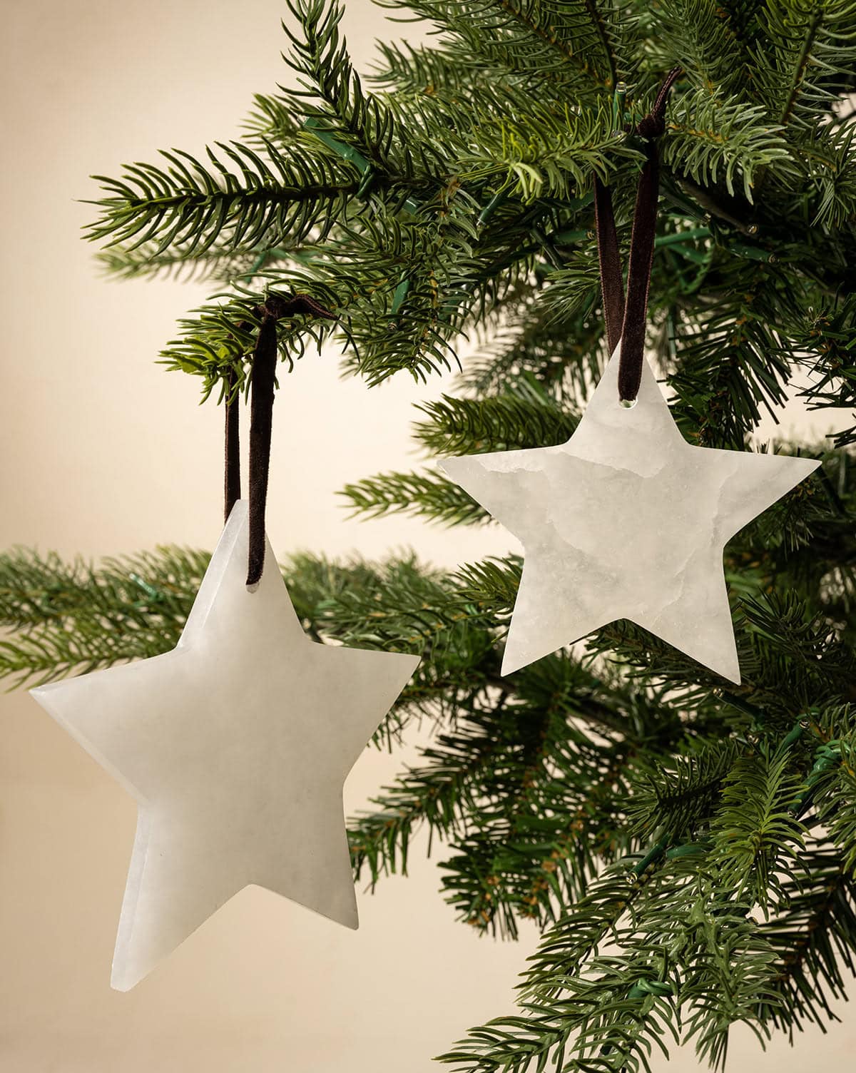 Gorgeous alabaster star ornaments adorn spruce holiday tree, hung from brown ribbons from Studio McGee.