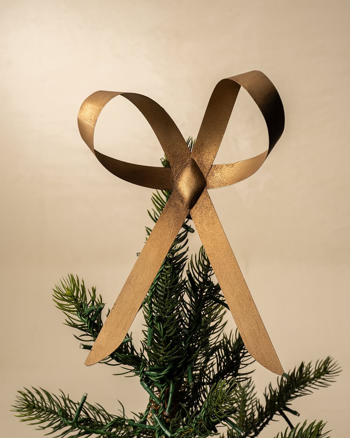 A beautiful brass bow tops a Christmas tree’s green branches, created from antique brass finish from Studio McGee.