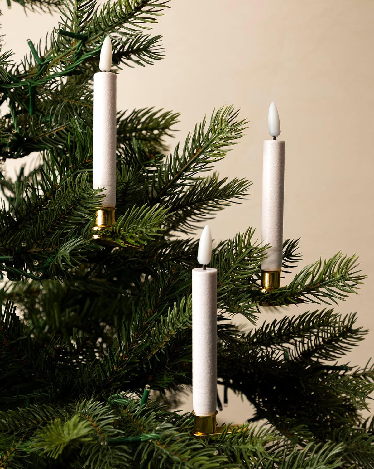 A set of 10 Christmas tree candle LED lights with brass fasteners are attached to the tree branches from Studio McGee.
