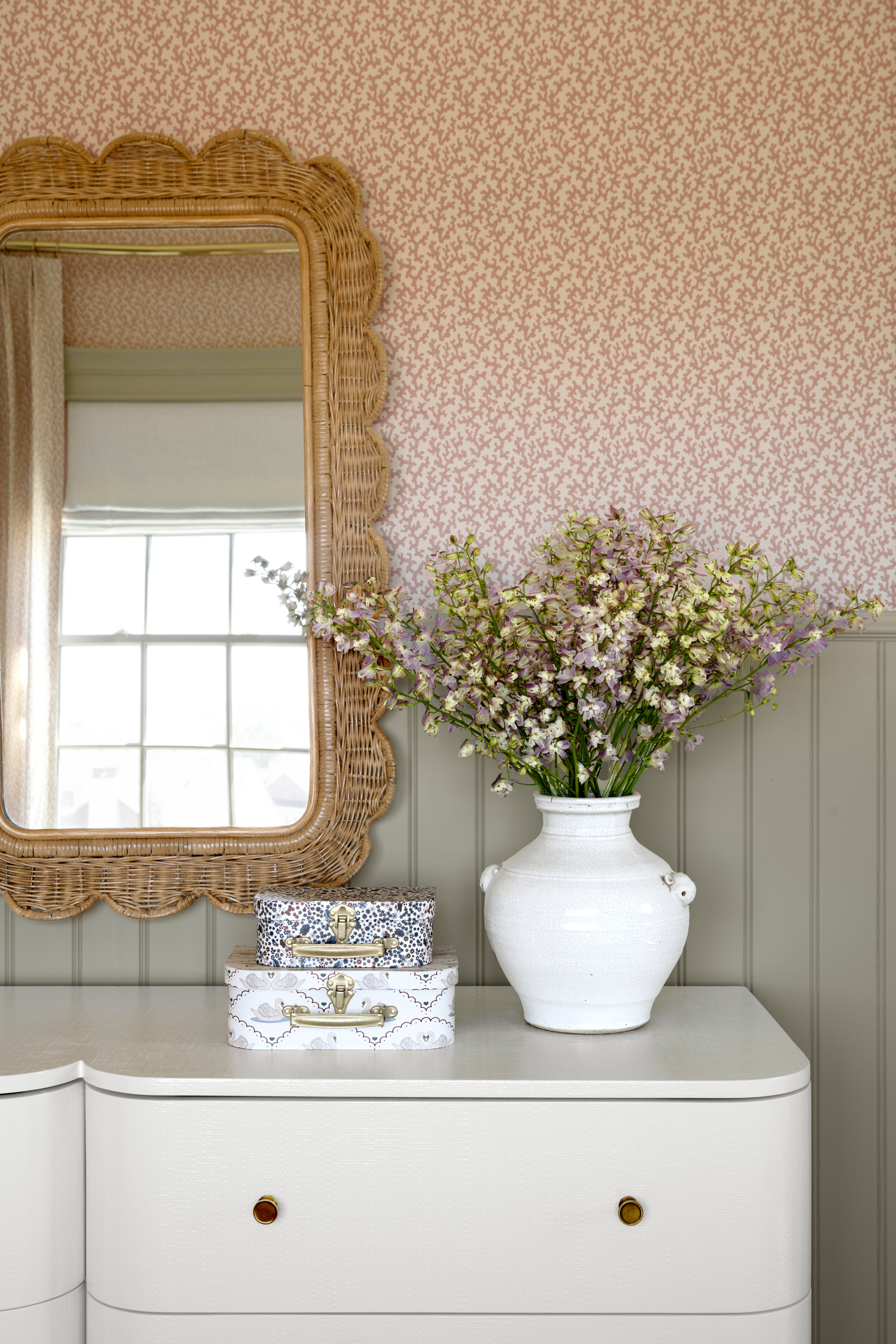 A vase of flowers on a chest of drawers with a decorative mirror from Studio McGee.