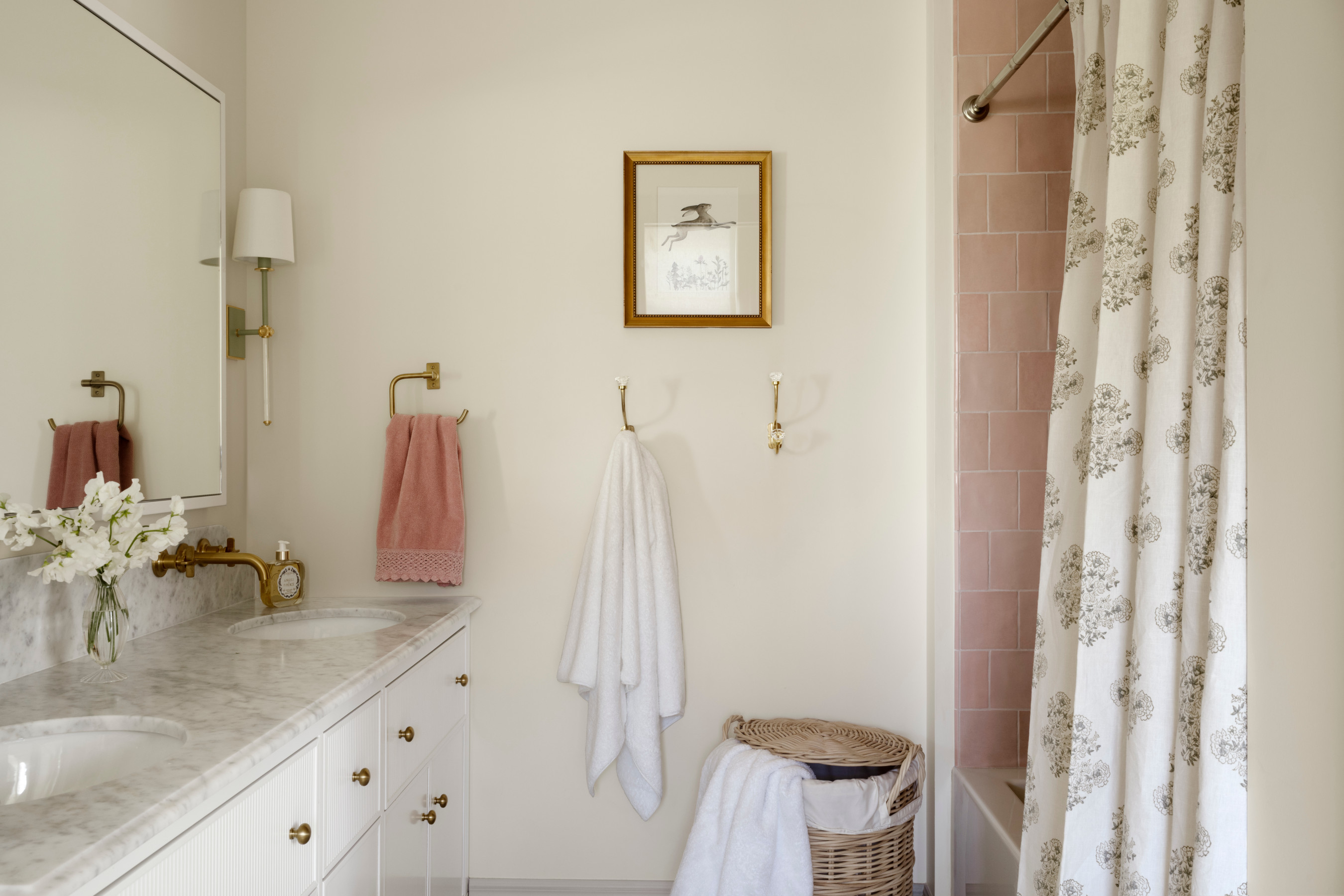 A simple design bathroom with a sink, cabinets and pink-tiled shower from Studio McGee.