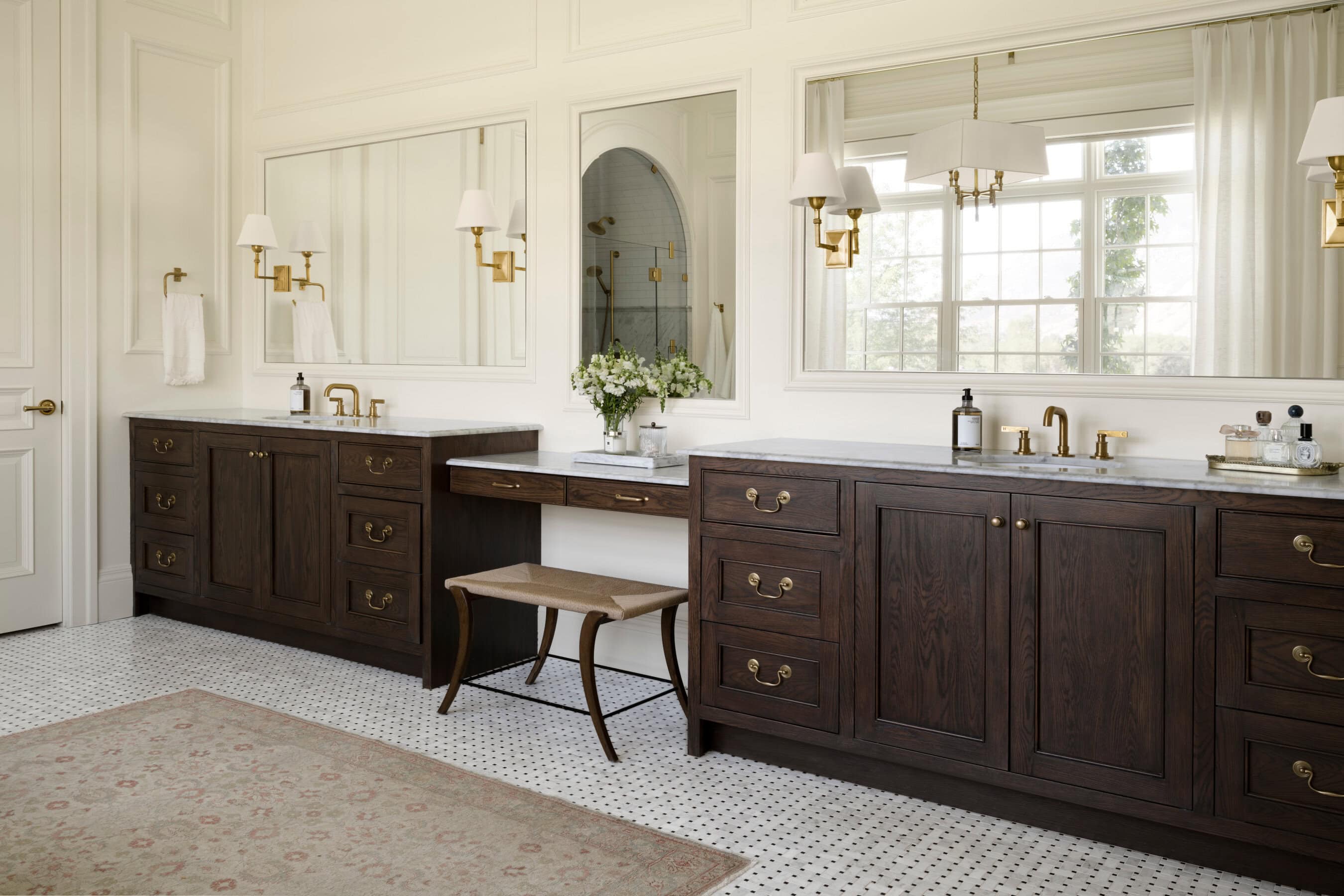 A bathroom with dark wood cabinets and a stool, by McGee & Co.