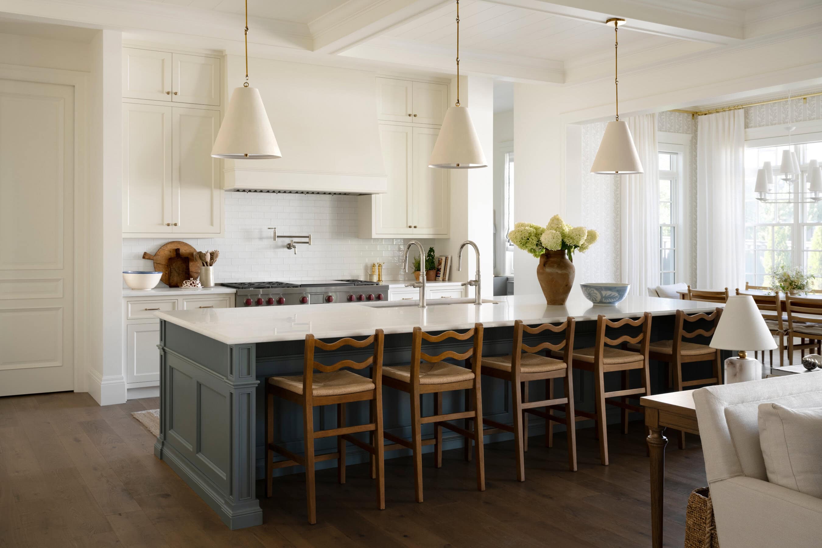 A kitchen with a large island and chairs, by McGee & Co.
