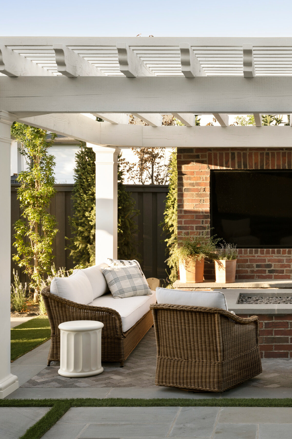 A pergola patio with a fireplace and wicker outdoor seating, from Studio McGee