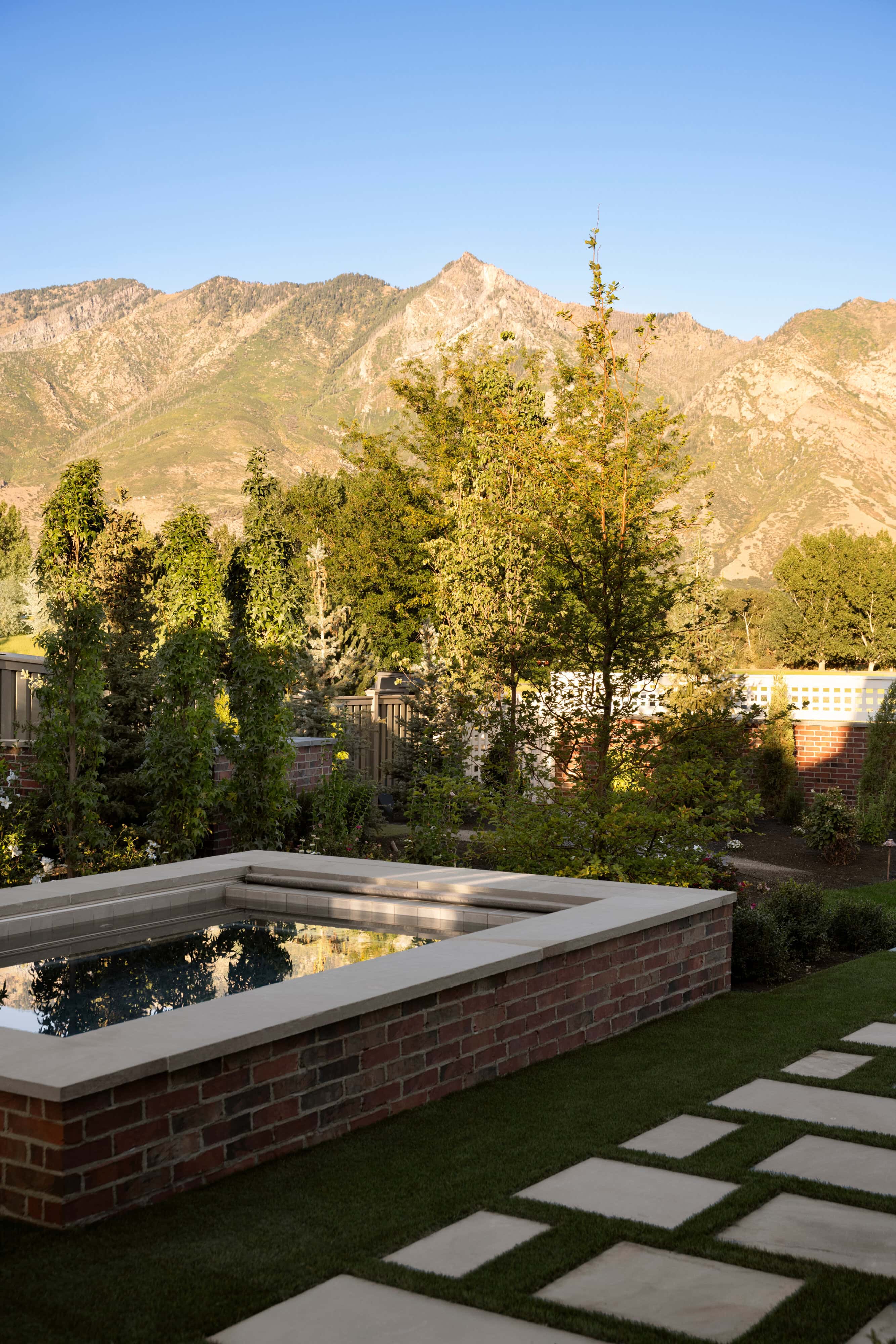 A backyard with a custom dipping pool surrounded by trees and mountains in the background, from Studio McGee.