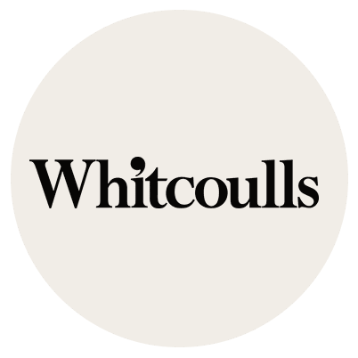 The Whitcoulls logo features the company name in bold black serif font, with a distinctive red dot above the i, set against a light beige circular background, by McGee & Co.