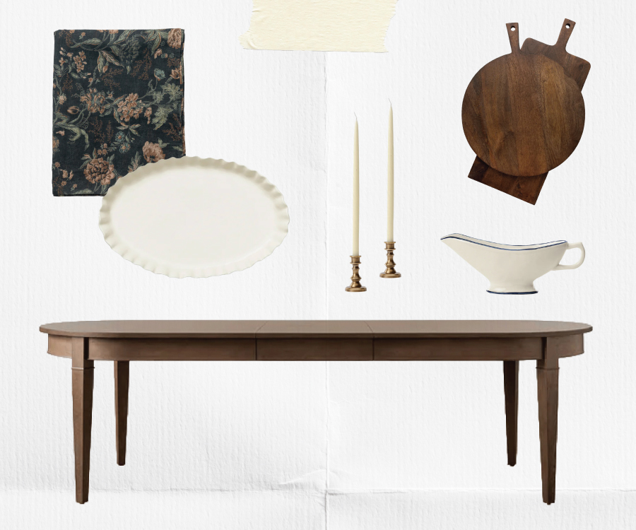 A dark wood dining table with a floral placemat, a white scalloped plate, two brass candlesticks with tall candles, a white gravy boat, and two wooden cutting boards arranged above it on a white background, by McGee & Co.