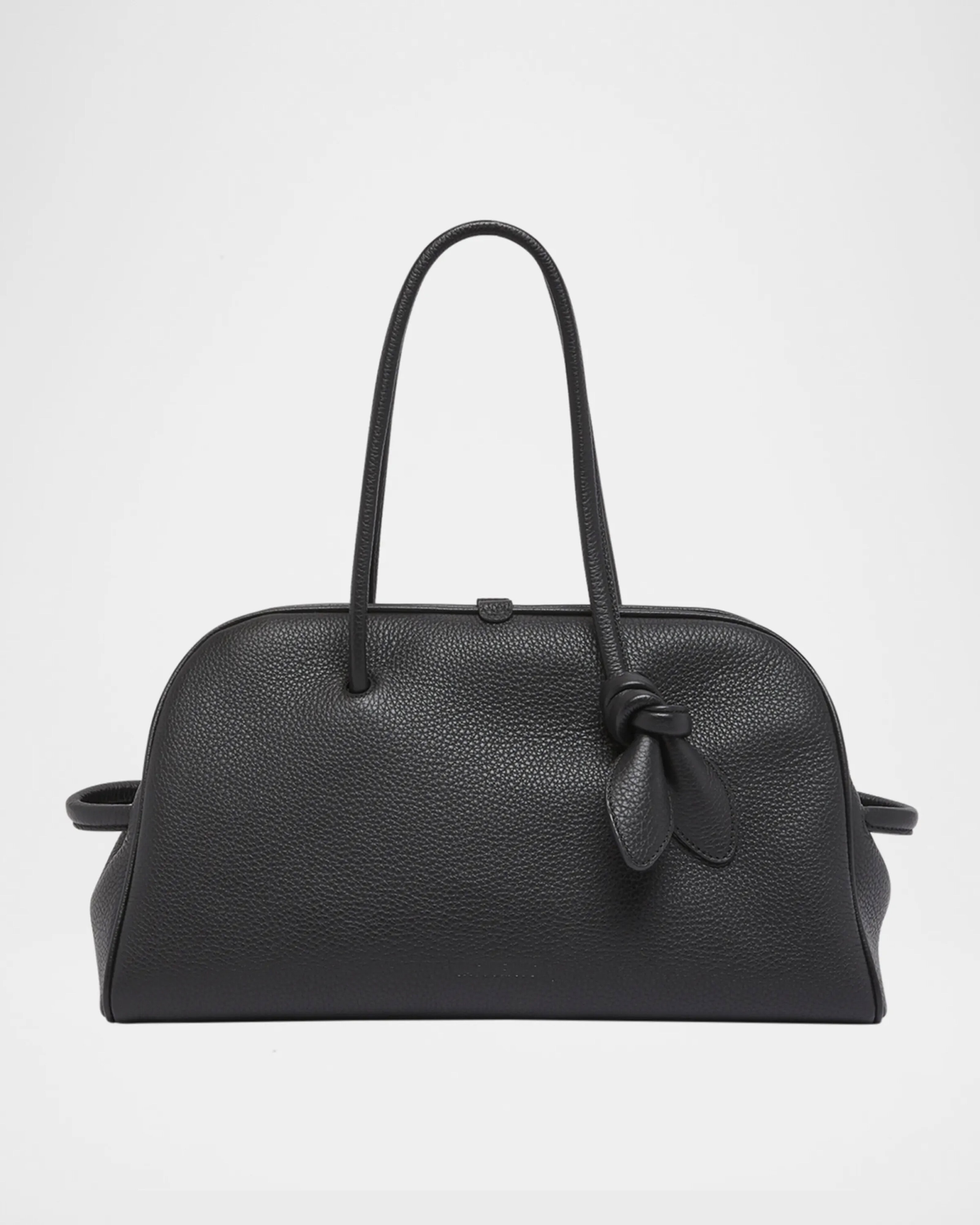 A black leather handbag with two long handles, one featuring a decorative knot, and a rounded, structured shape against a plain white background, by McGee & Co.
