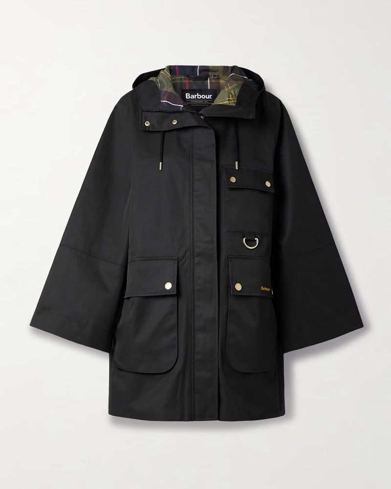 A black hooded utility jacket with multiple front pockets, gold snap buttons, a ring detail, and plaid lining visible at the collar. The brand Barbour is visible on the inside collar, by McGee & Co.
